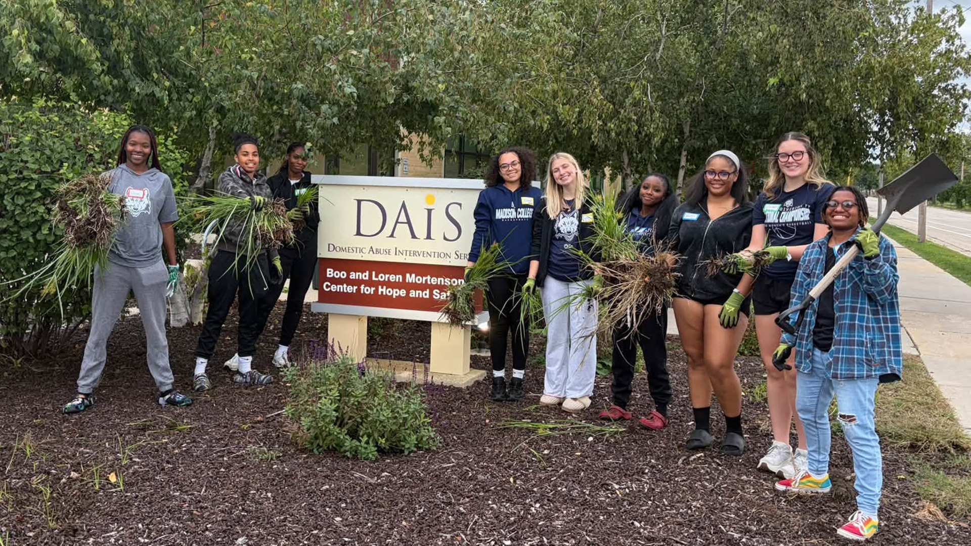 Members of the women's basketball team work to clean up the landscaping at DAIS of Madison.