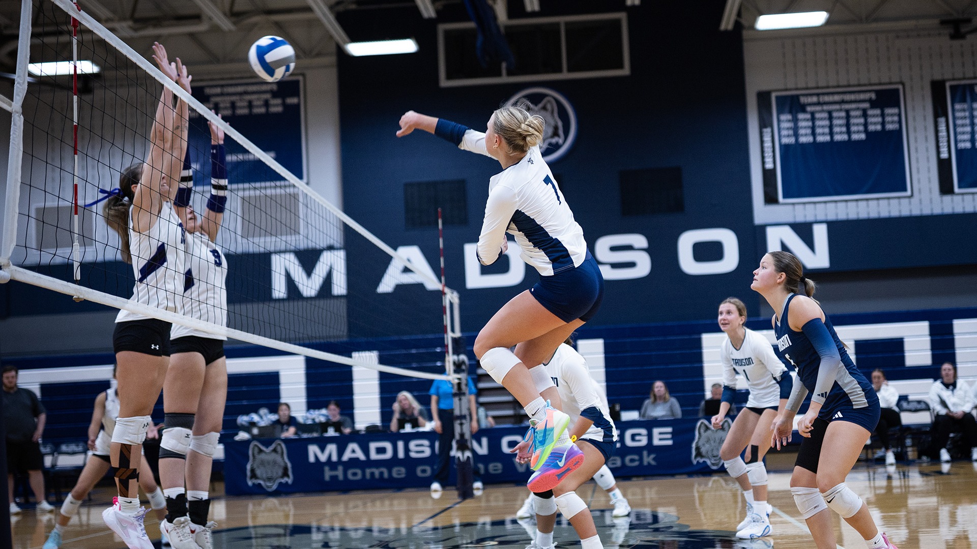 Sam Schultz hits an attack as teammate look on and opponent attempt to block.