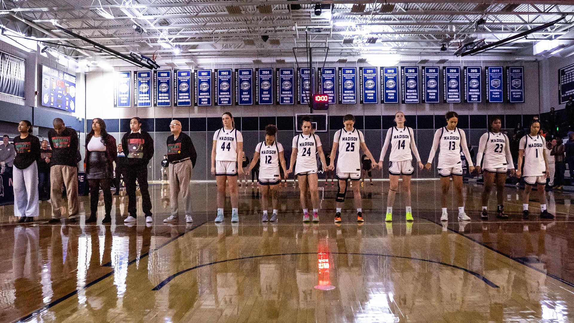 The women's basketball team stands during the national anthem at a home game.