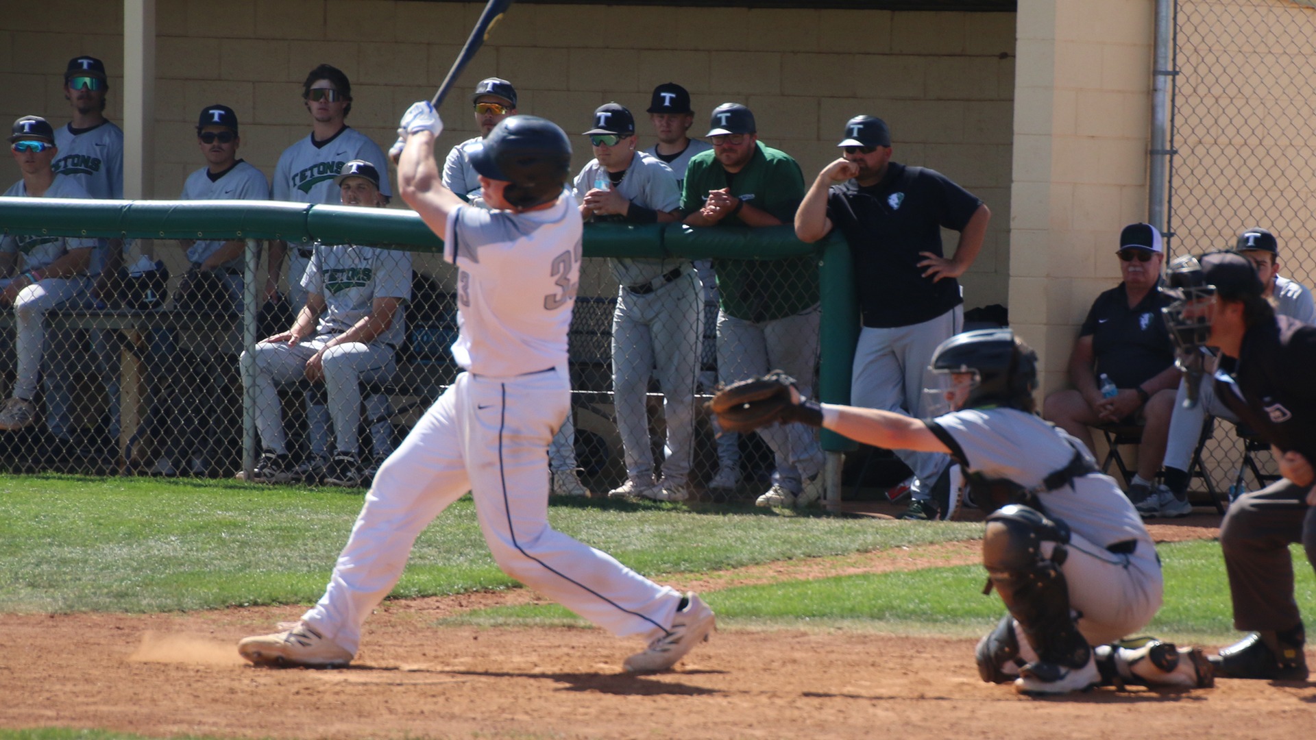 Ian Salvesen hits a ball into play as the catcher and umpire look on