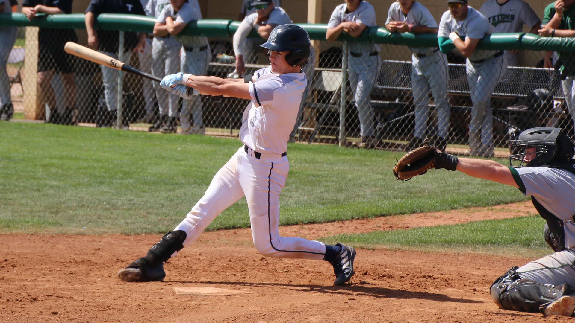 Jonah Roloff finishes a swing as he hits the ball with teammates looking on