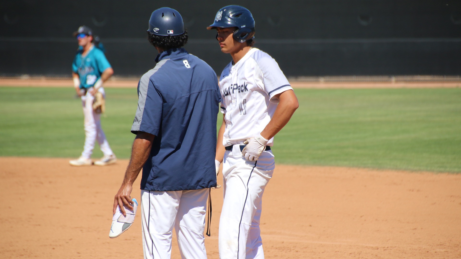 Paul Nuetzel stands at first base and talks with assistant coach Cam Cratic