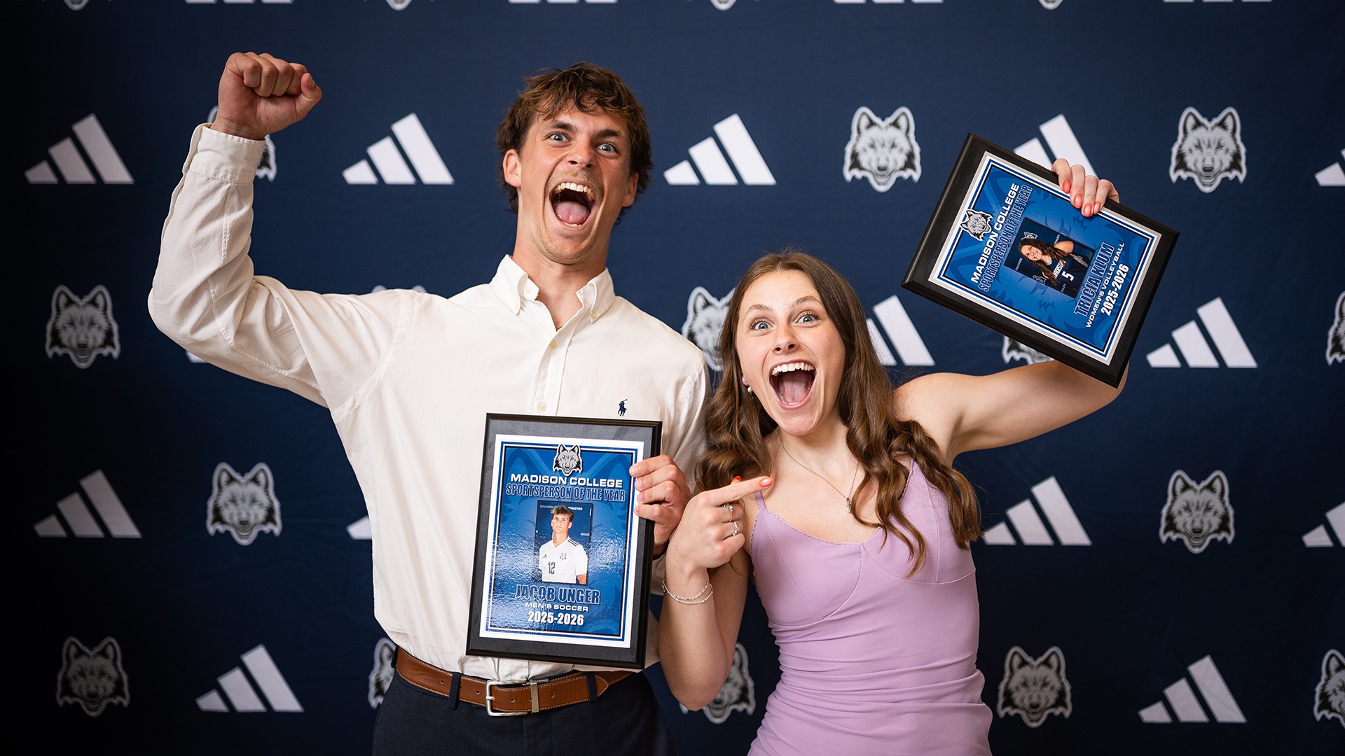 Men's soccer player Jacob Unger and women's volleyball player Tricia Klum pose in a silly manner with their 2026 Sportspeople of the Year awards in front of a backdrop at the The Wolfie Awards.