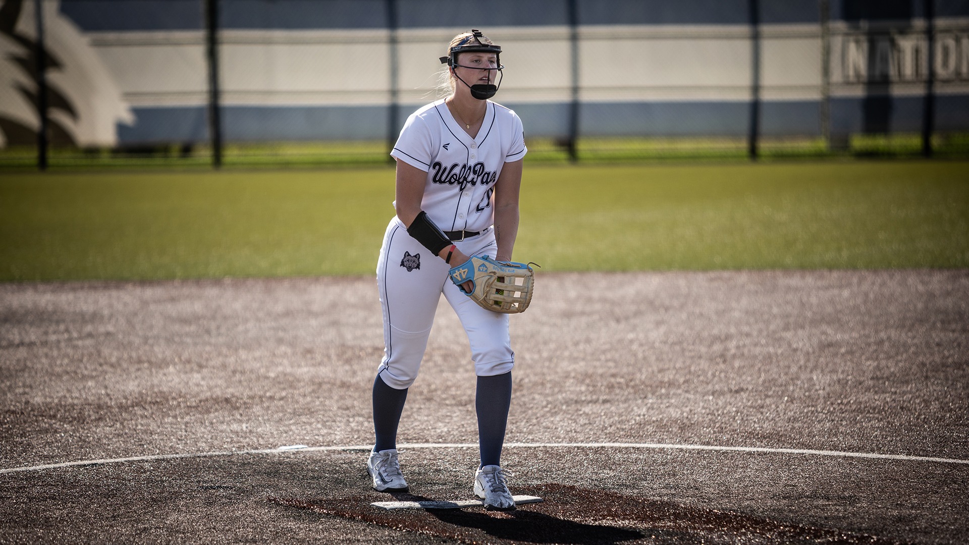 Sophie Golembiewski prepares to throw a pitch as she hold the ball in her glove above her knee.