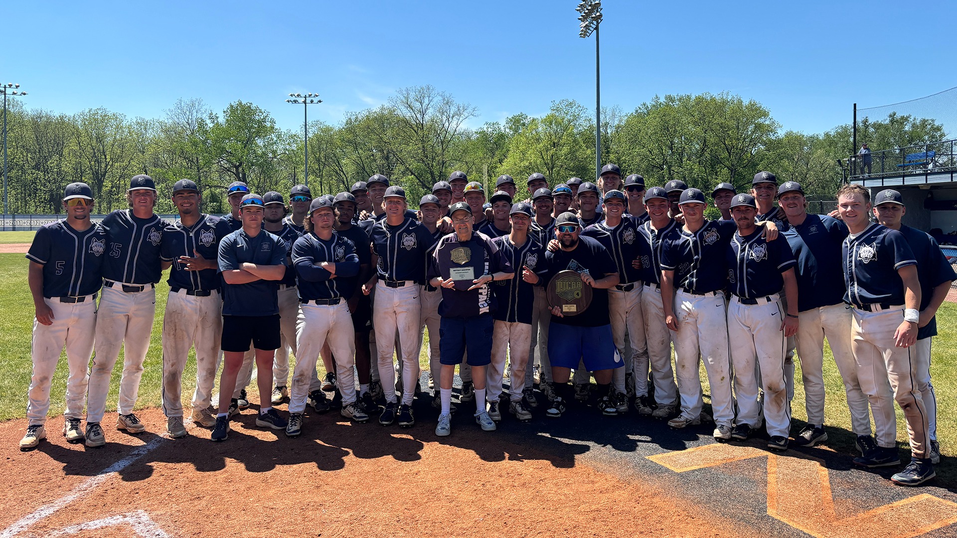 Madison College baseball players, coaches, and managers pose with championship trophy after winning the Region 4 Tournament.