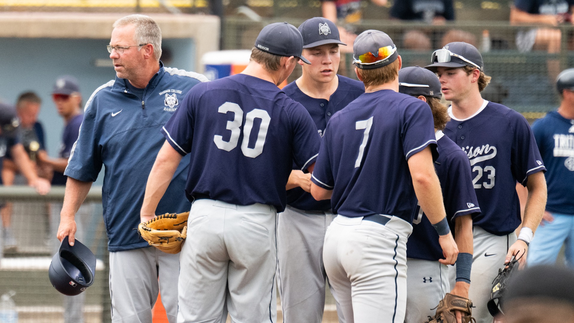 Coach Mike Davenport leaves a meeting on the pitcher's mound with players at the NJCAA World Series