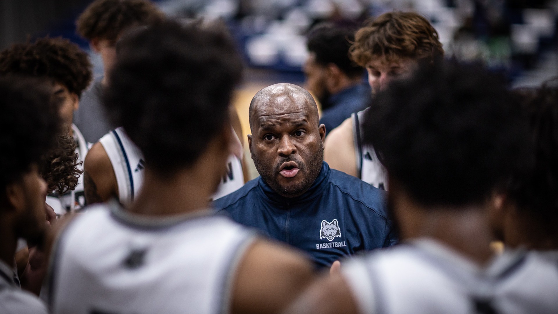 Jason Roscoe talks to the men's basketball team during a timeout.