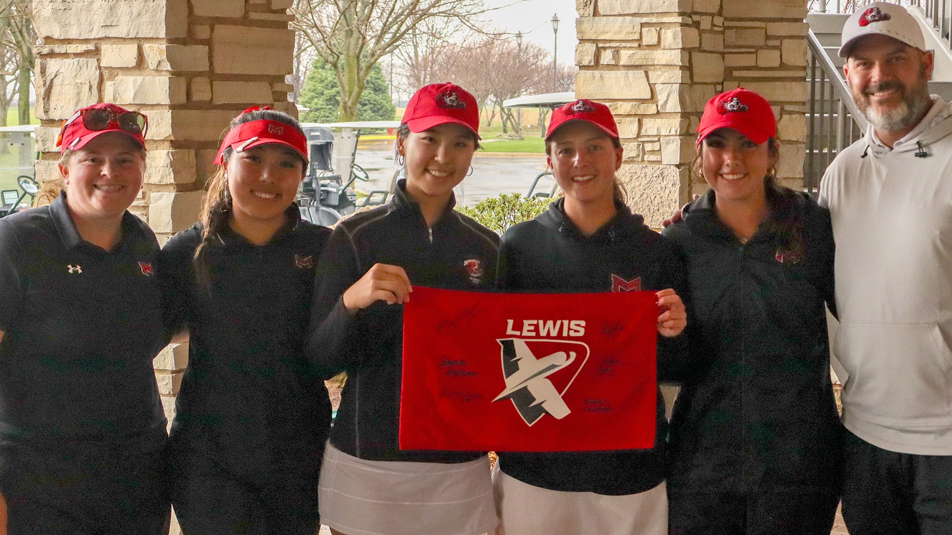 Saints women's golf with Flyer Invitational flag 2026