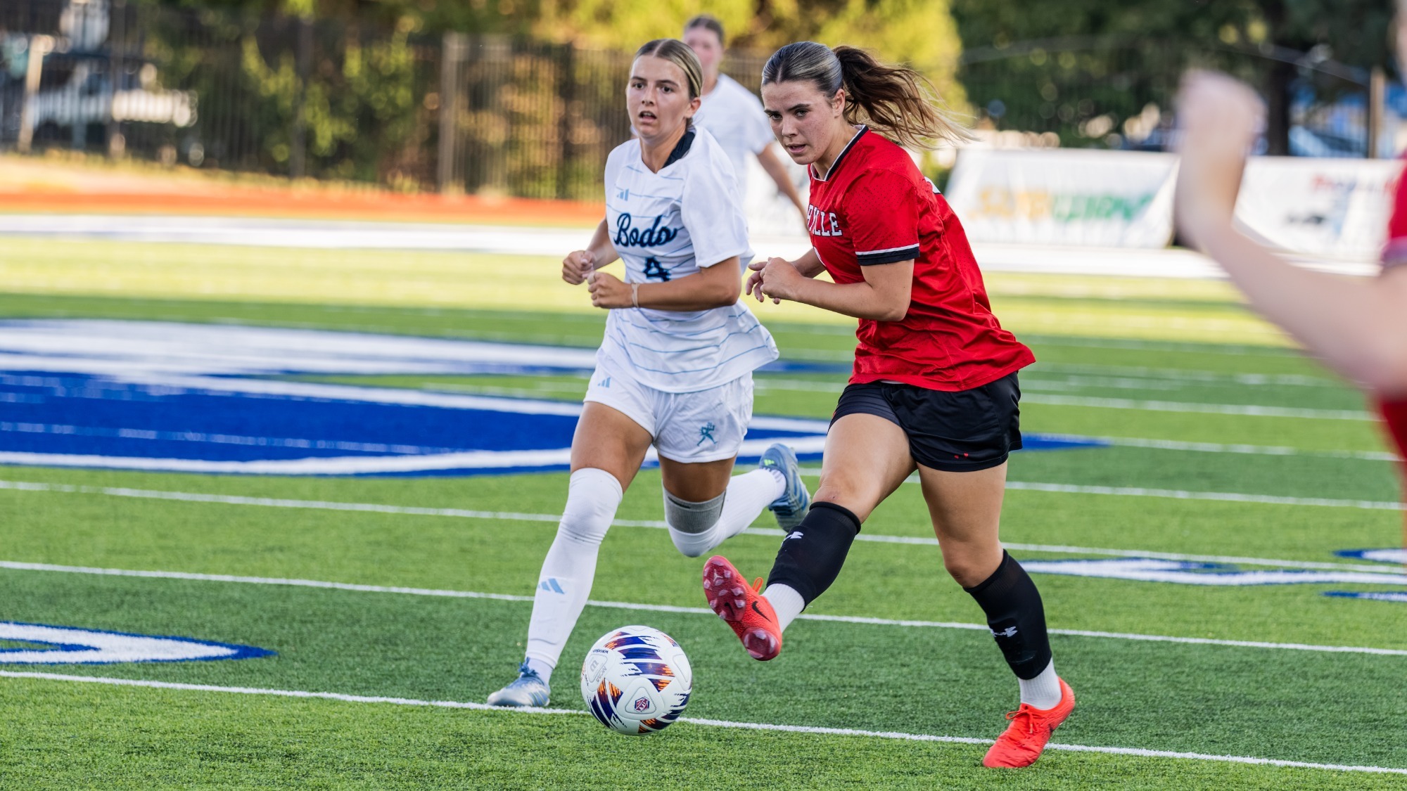Isabella Lobley kicks the ball upfield as she is chased down by a Washburn player