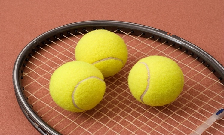 Three tennis balls on a racket head