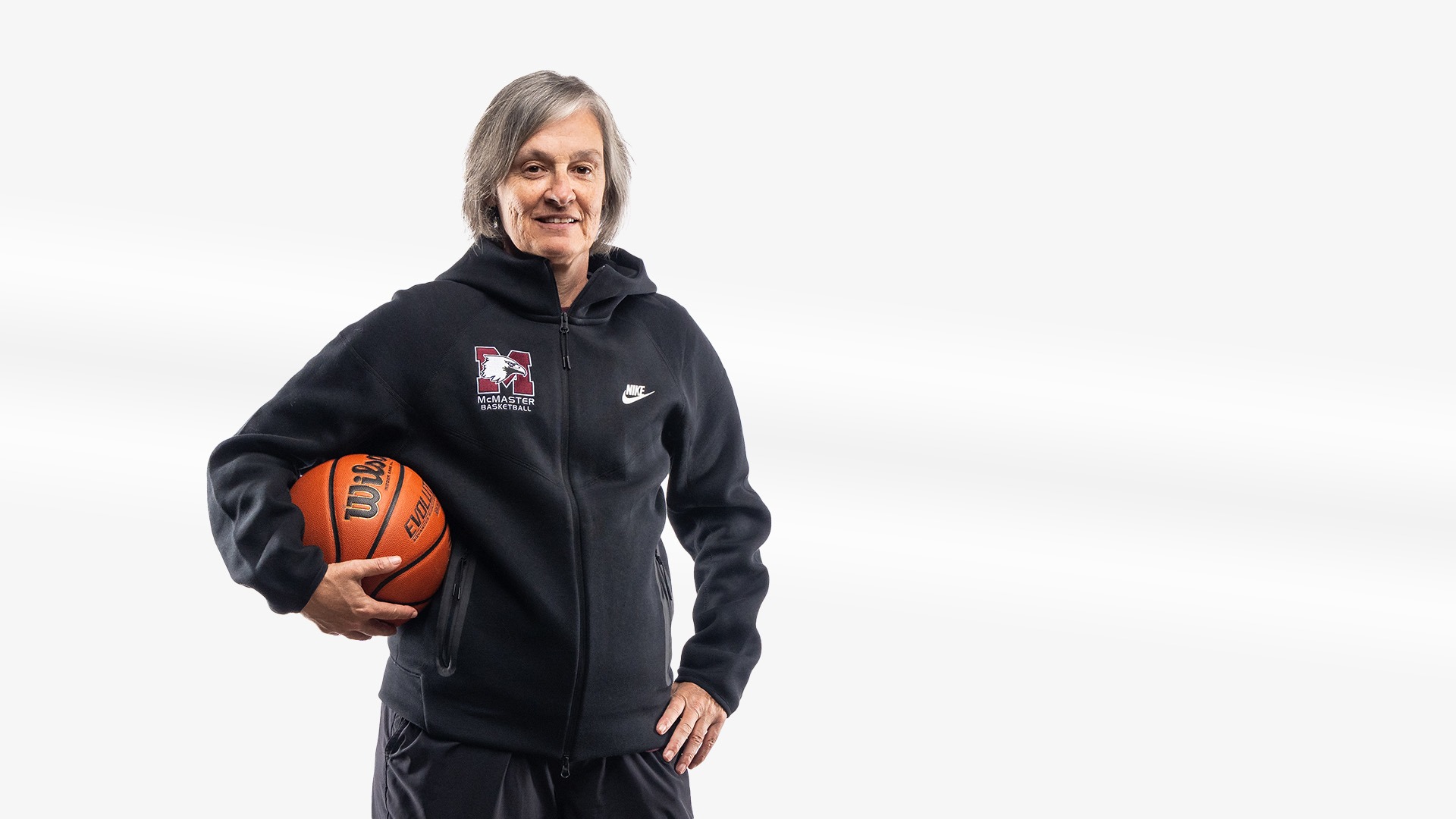 Theresa Burns poses in front of a white background holding a basketball.