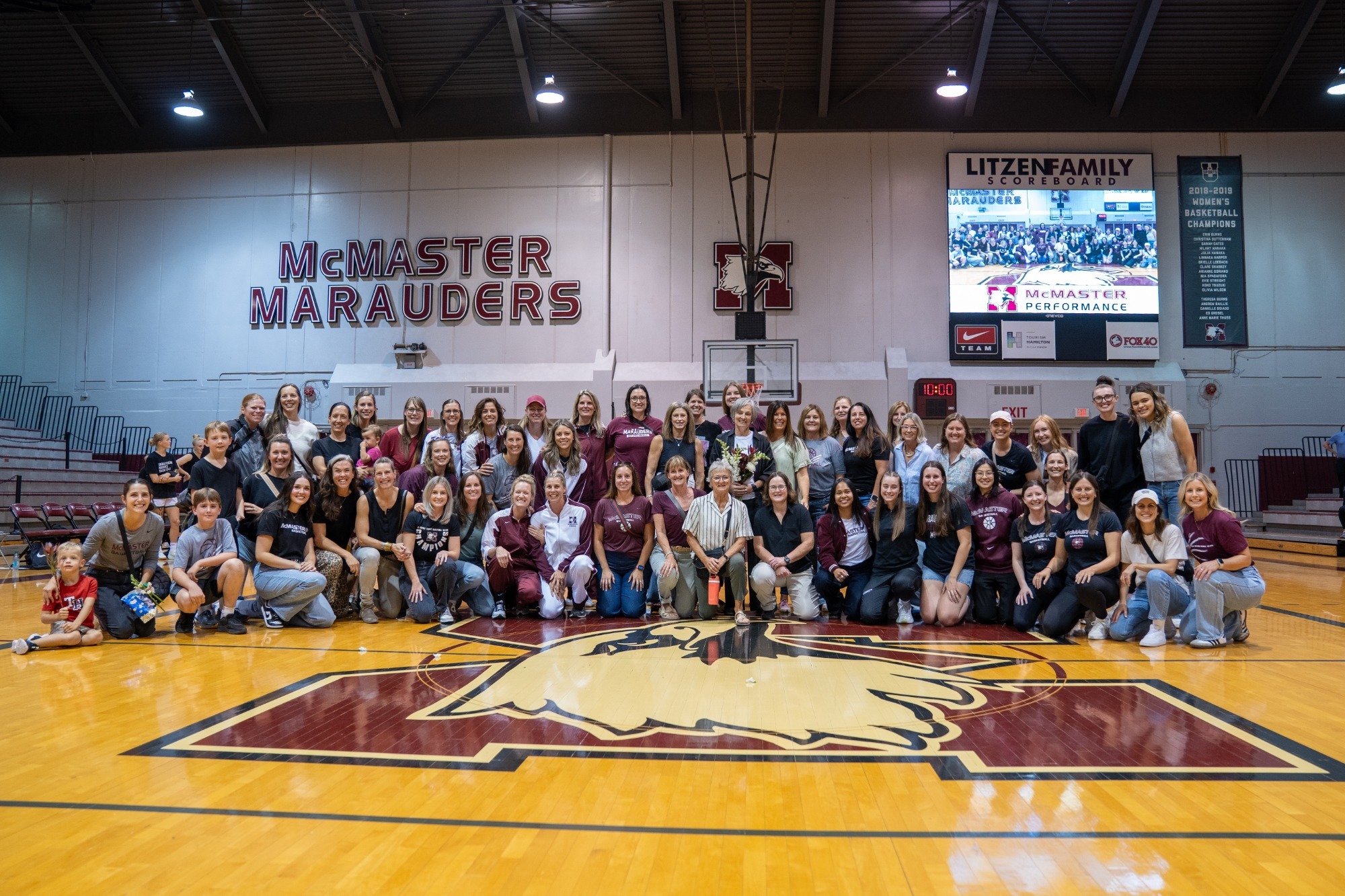 Theresa Burns women's basketball alumni pose for a group photo during her tribute game