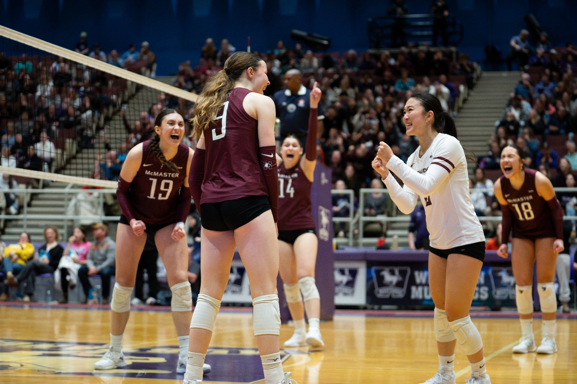 The McMaster women's volleyball players on the court celebrate a point