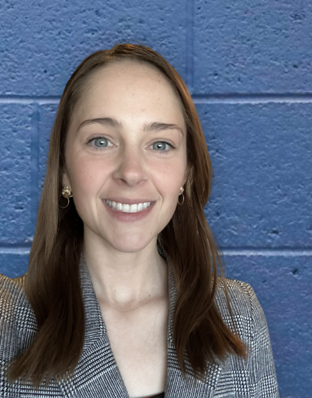 Paget Collins Headshot in front of a blue brick wall in Lockridge Arena