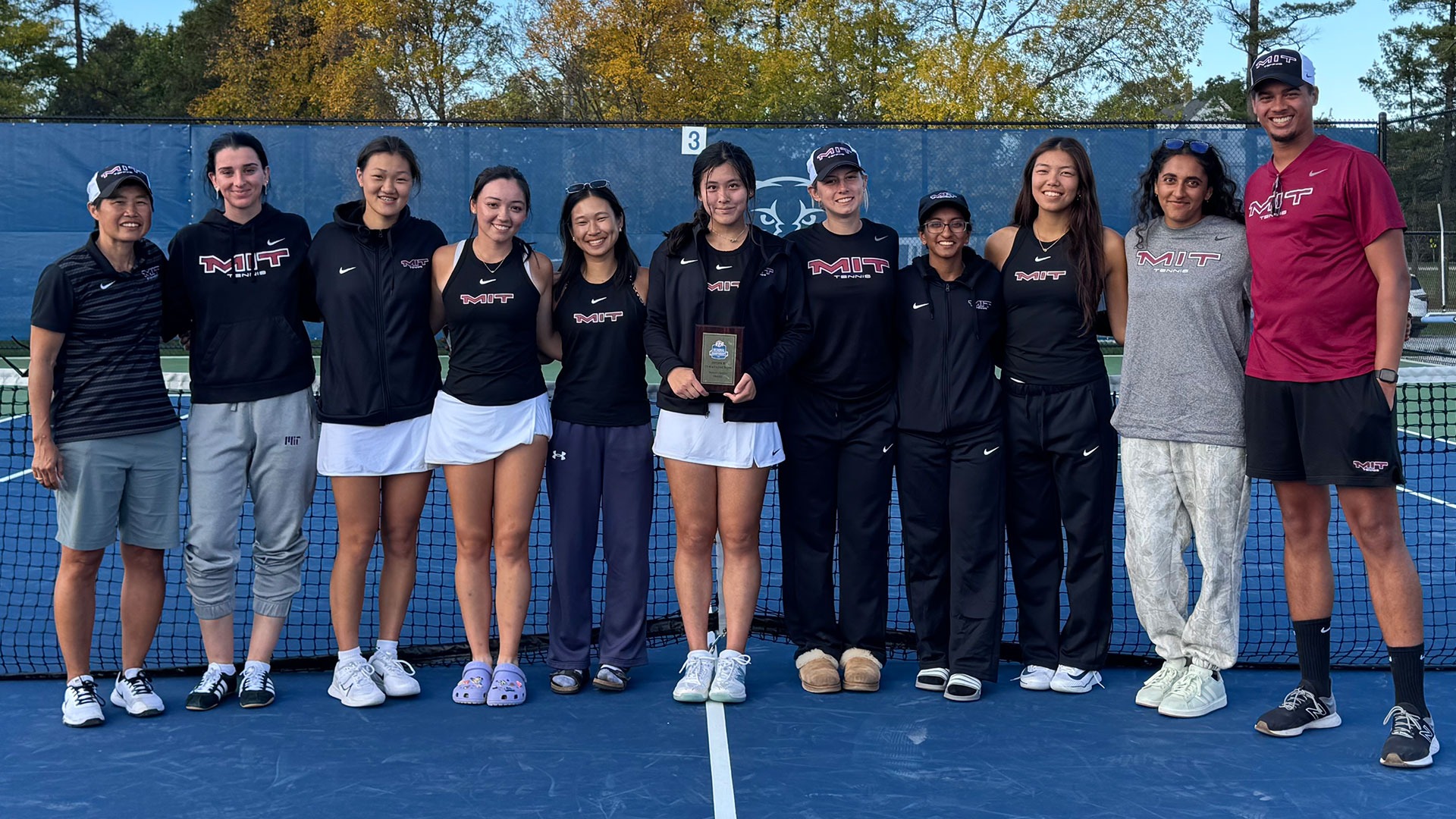 The MIT women's tennis team standing around Fiona Lee who is holding the ITA singles runner-up plaque