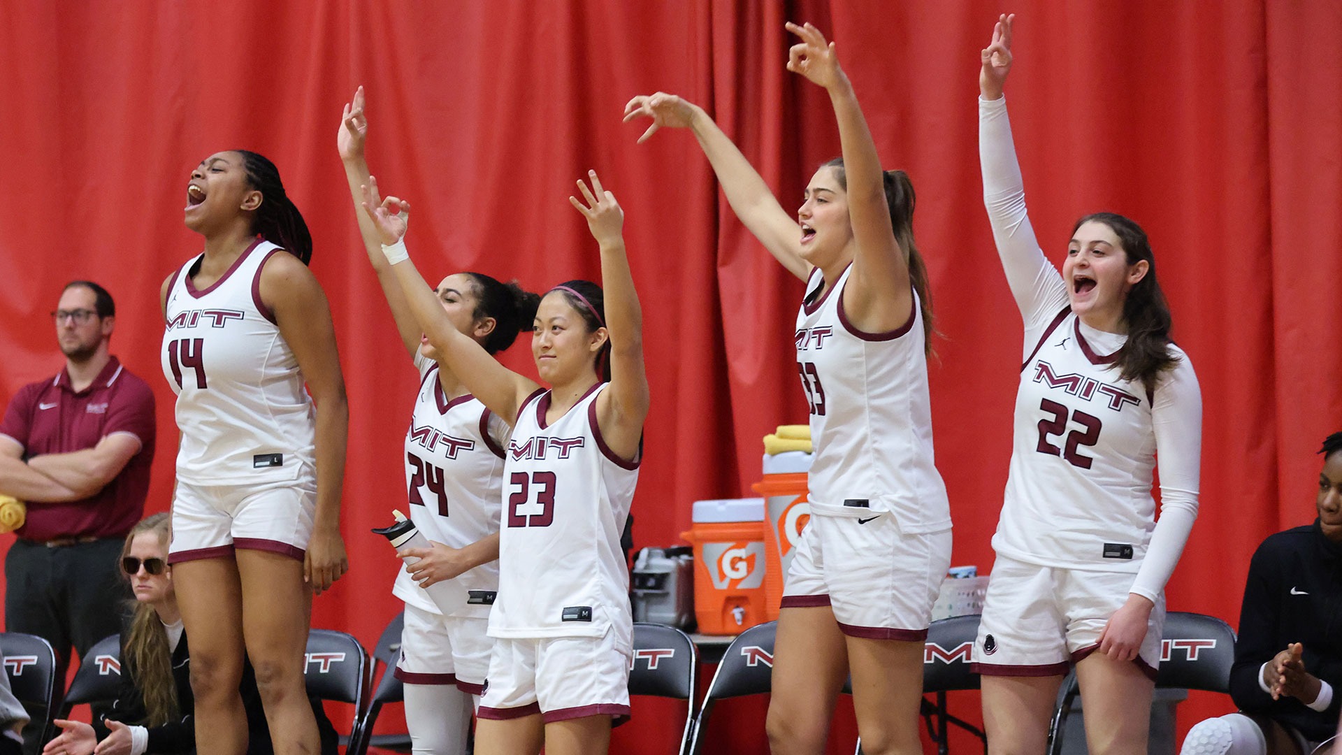 Members of the women's basketball team celebrating at the bench