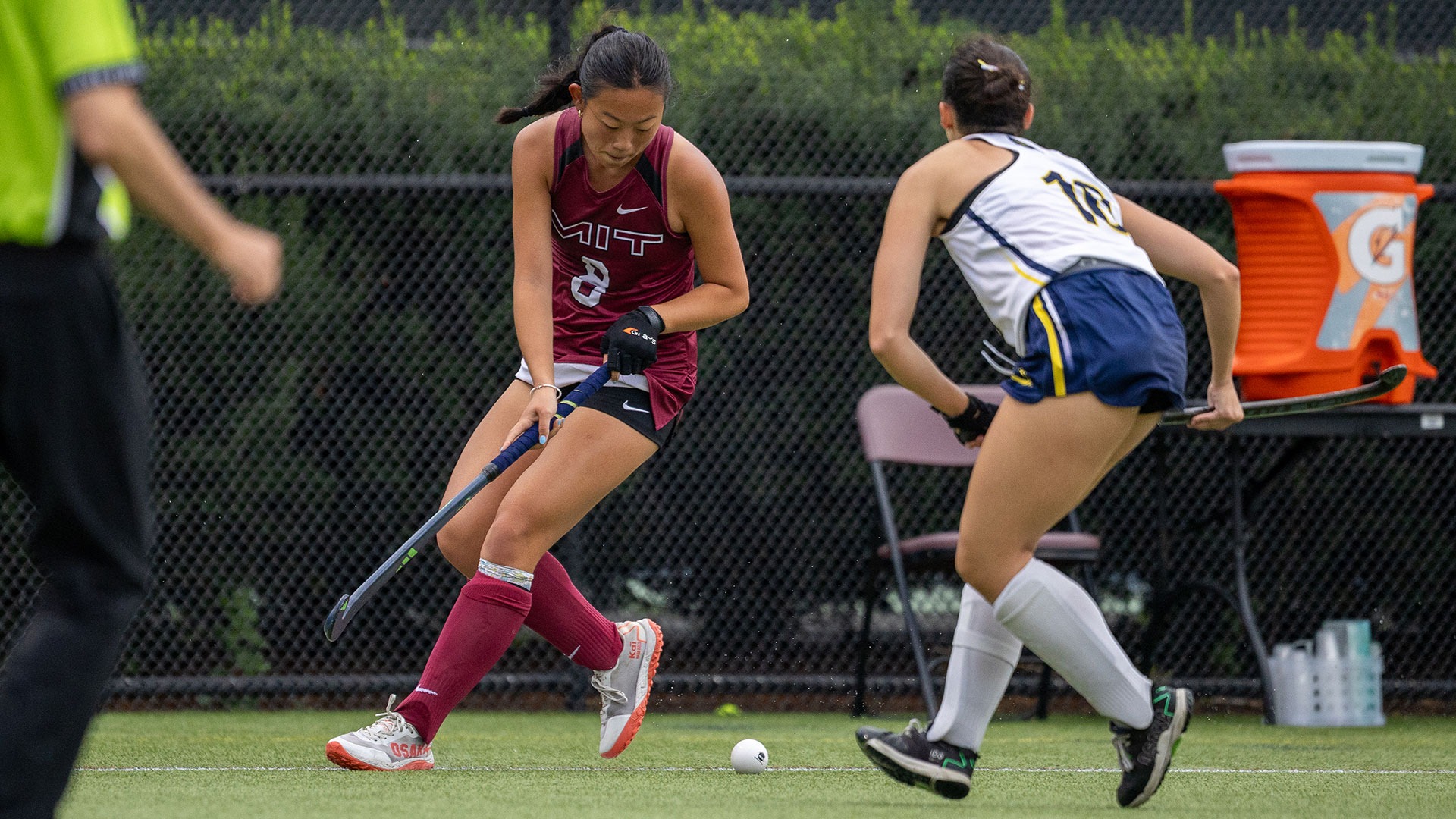 Meredith Wu in the process of hitting a ball with her field hockey stick while being defended