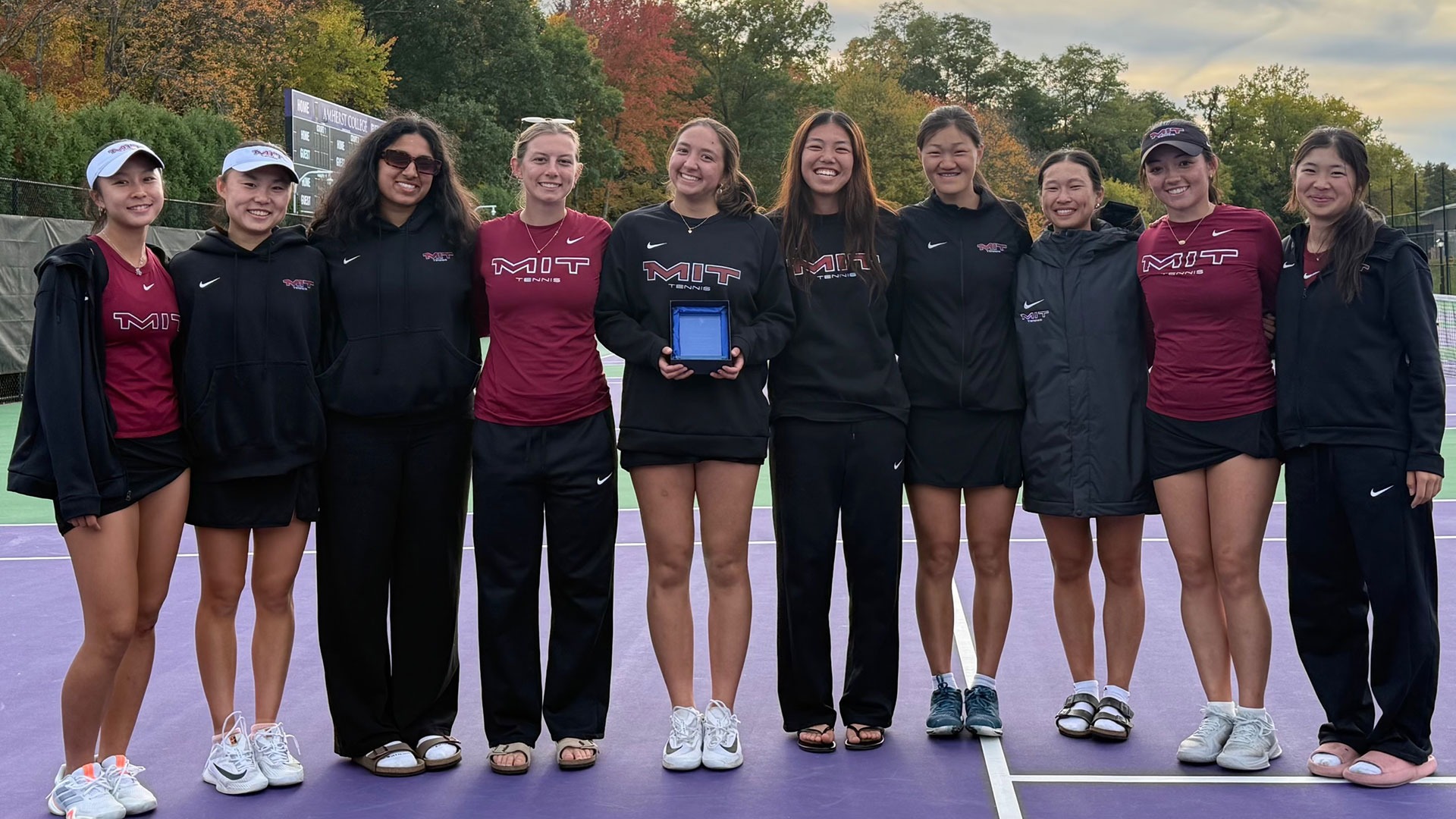 Members of the women's tennis team in a group photo with Anselma Petrie holding the Christine Davis Sportsmanship Award