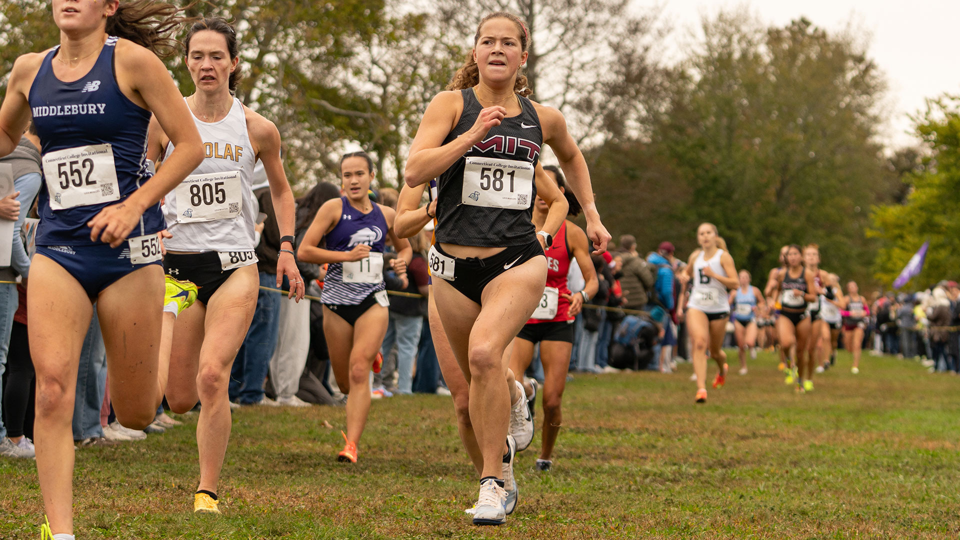 Liv Girand running at a cross country race for MIT, passing other runners near the finish