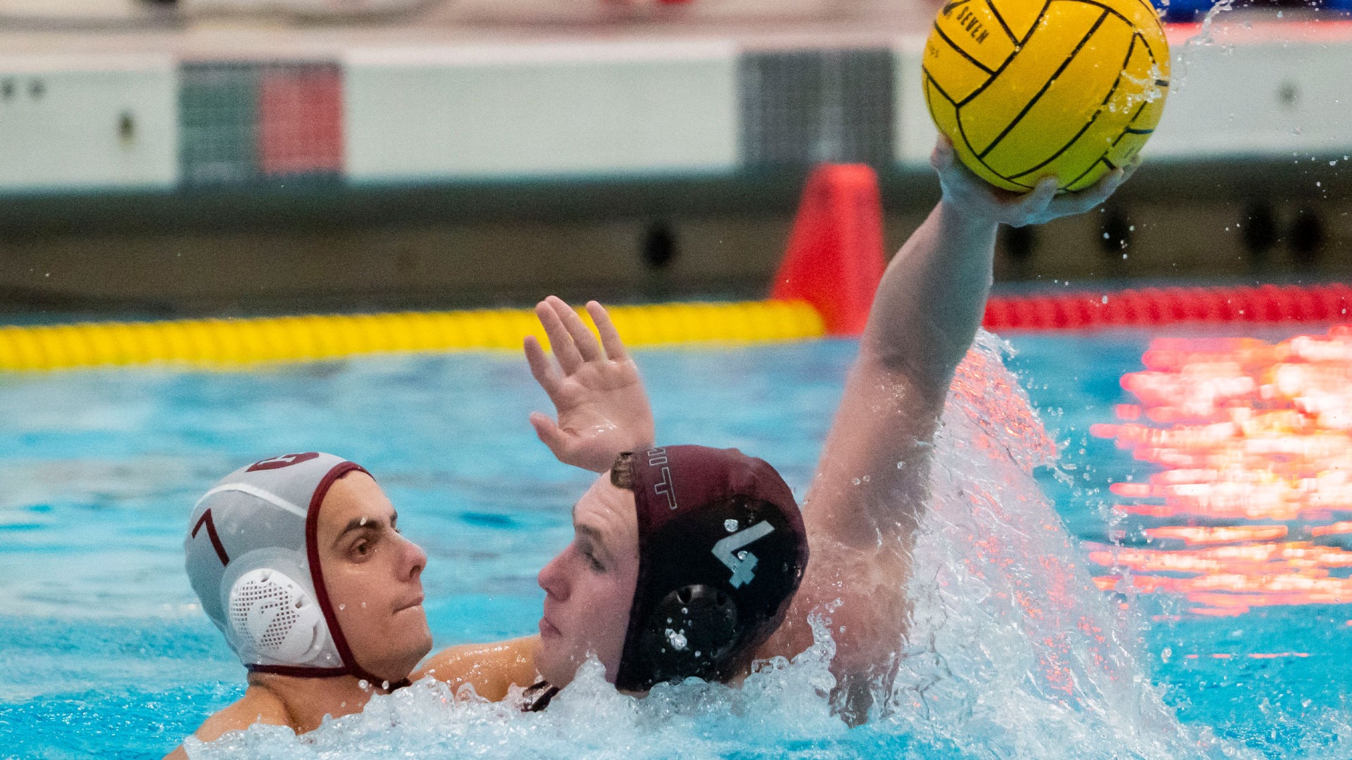 Jake Schweizer being defended by an opponent while holding a water polo ball
