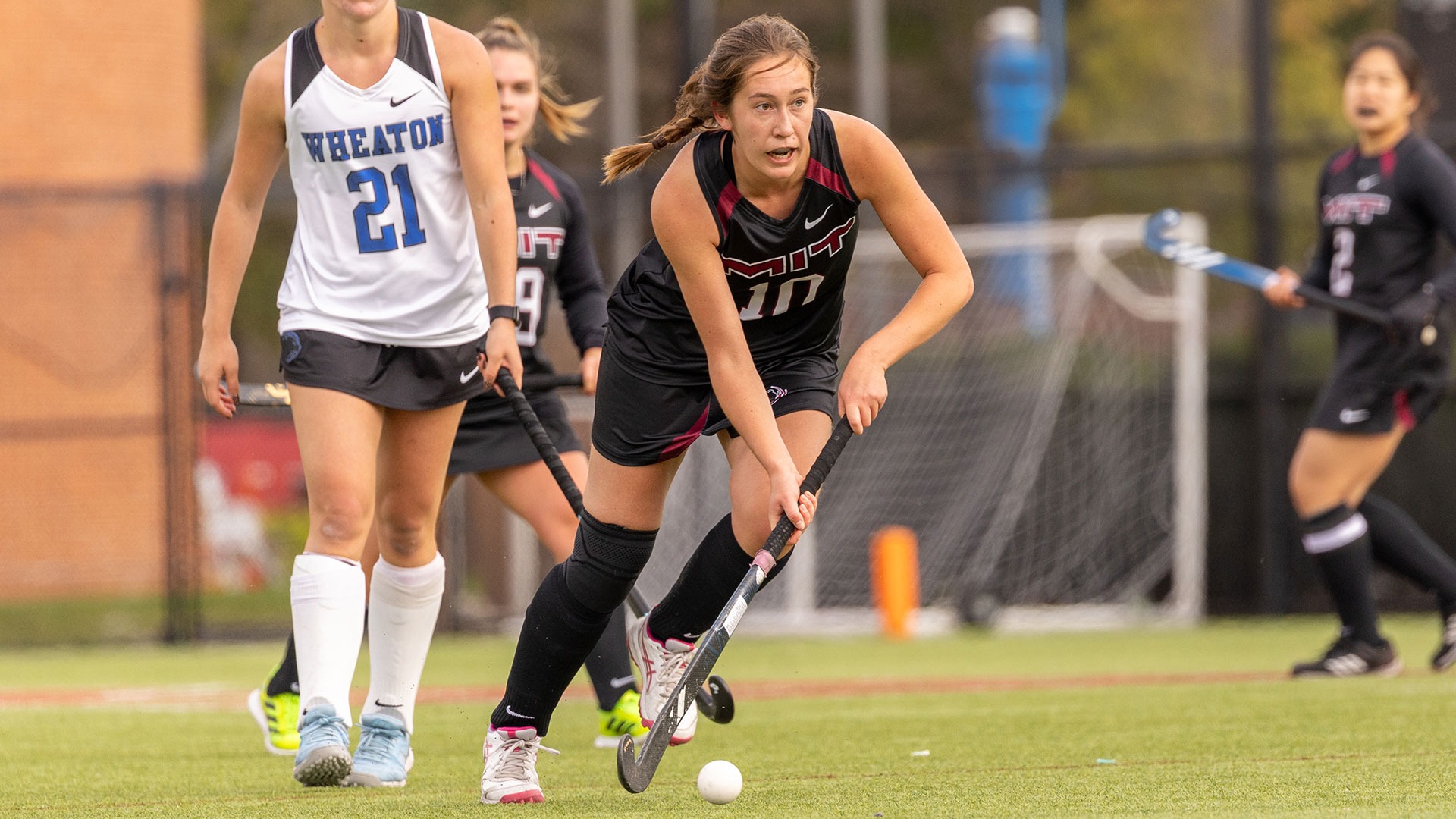Ingrid Tomovski running down the field after a ball while holding her field hockey stick