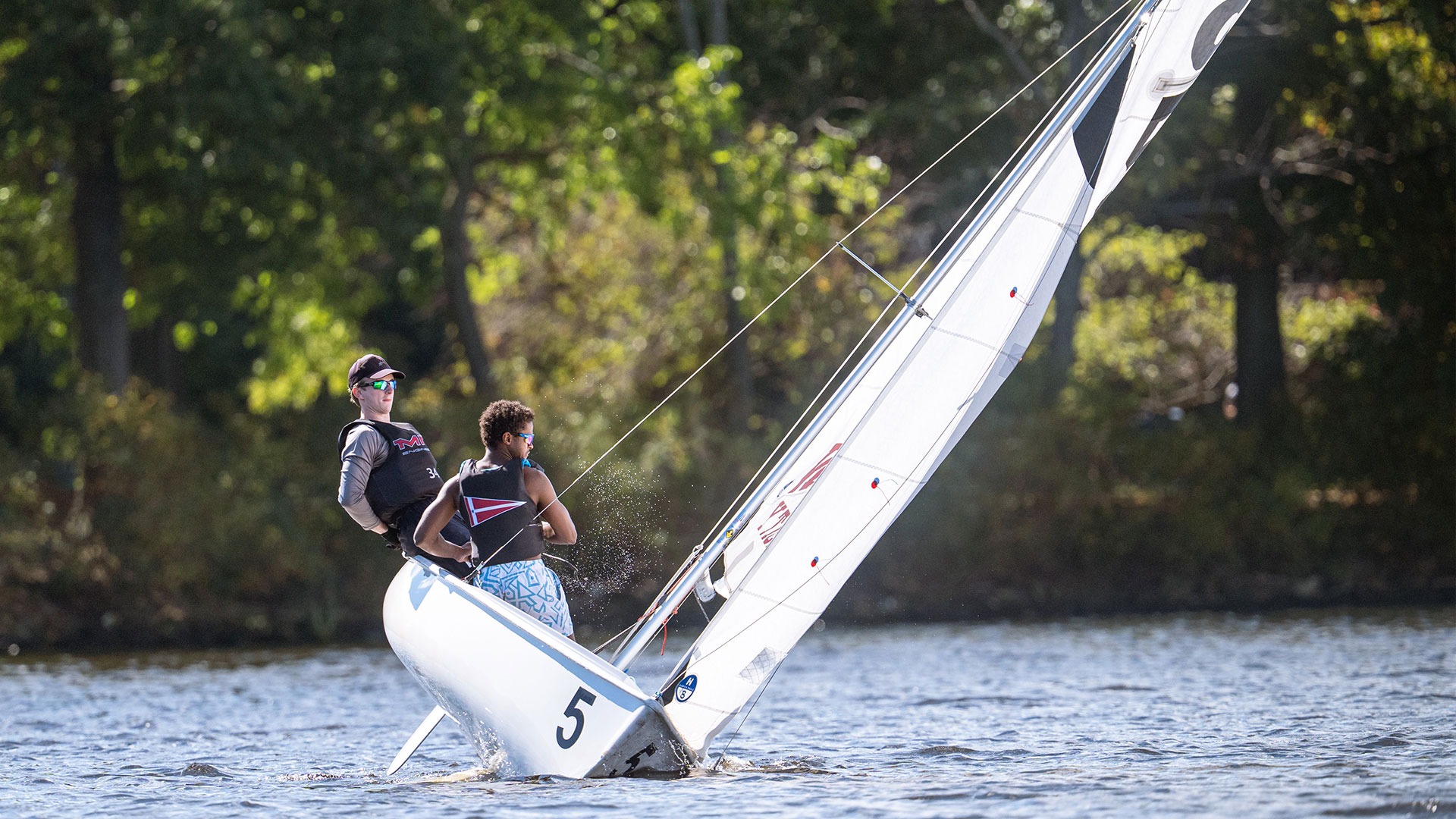 Two MIT sailors manuevering the sailboat on the river