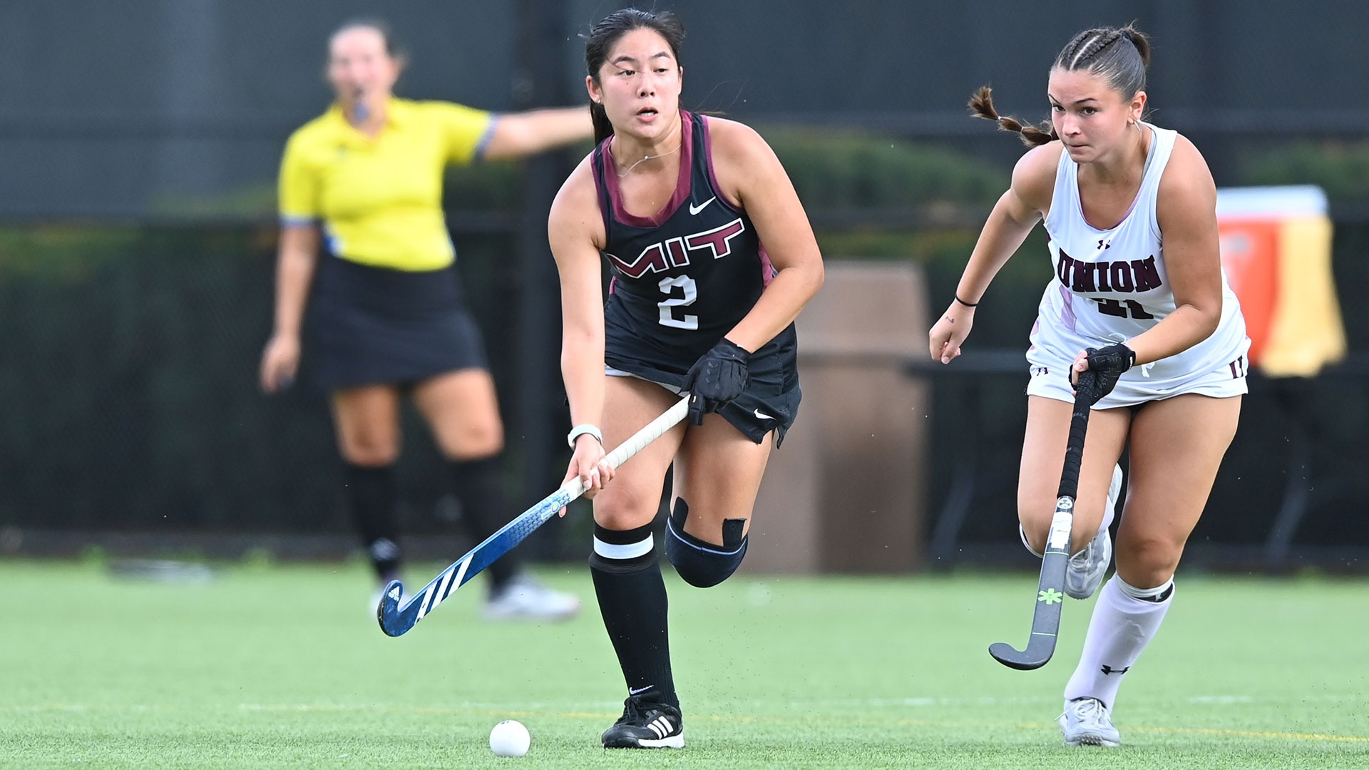 Audrey Oh running down the field holding her field hockey stick