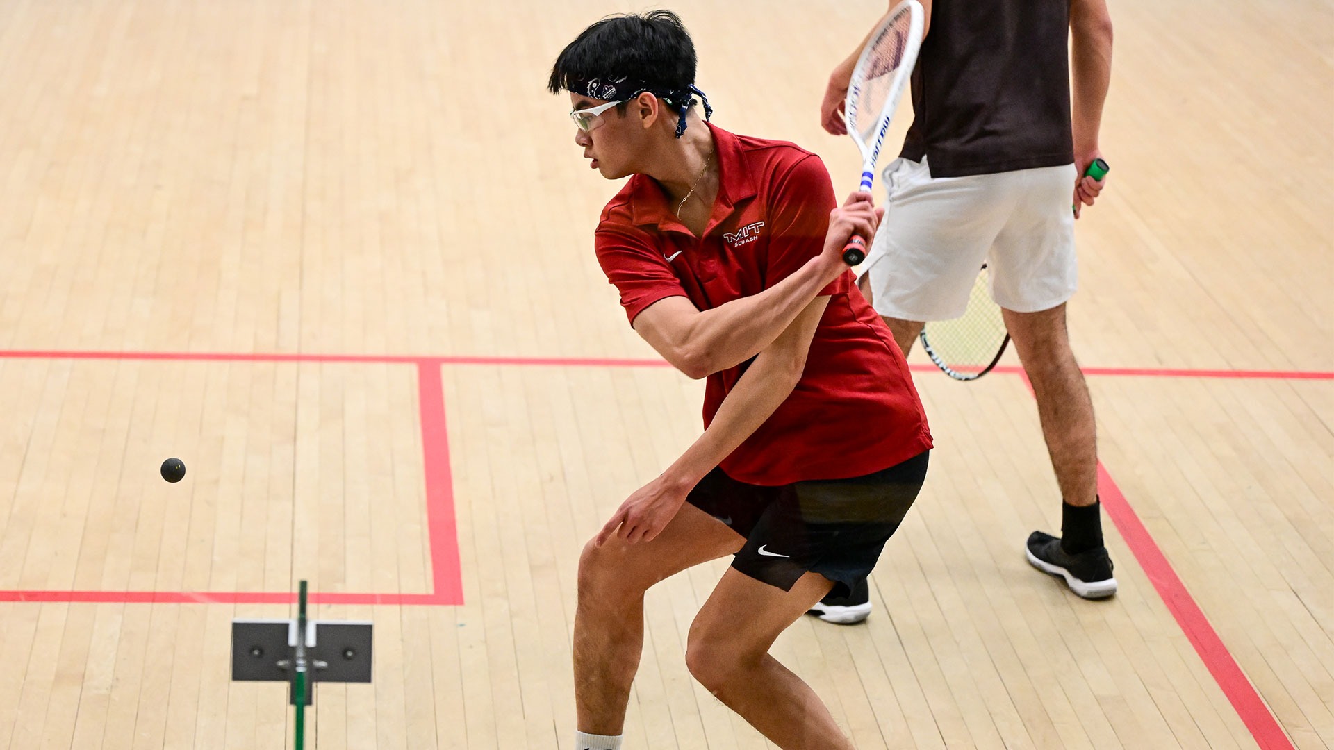 Ethan Chan hitting a squash ball