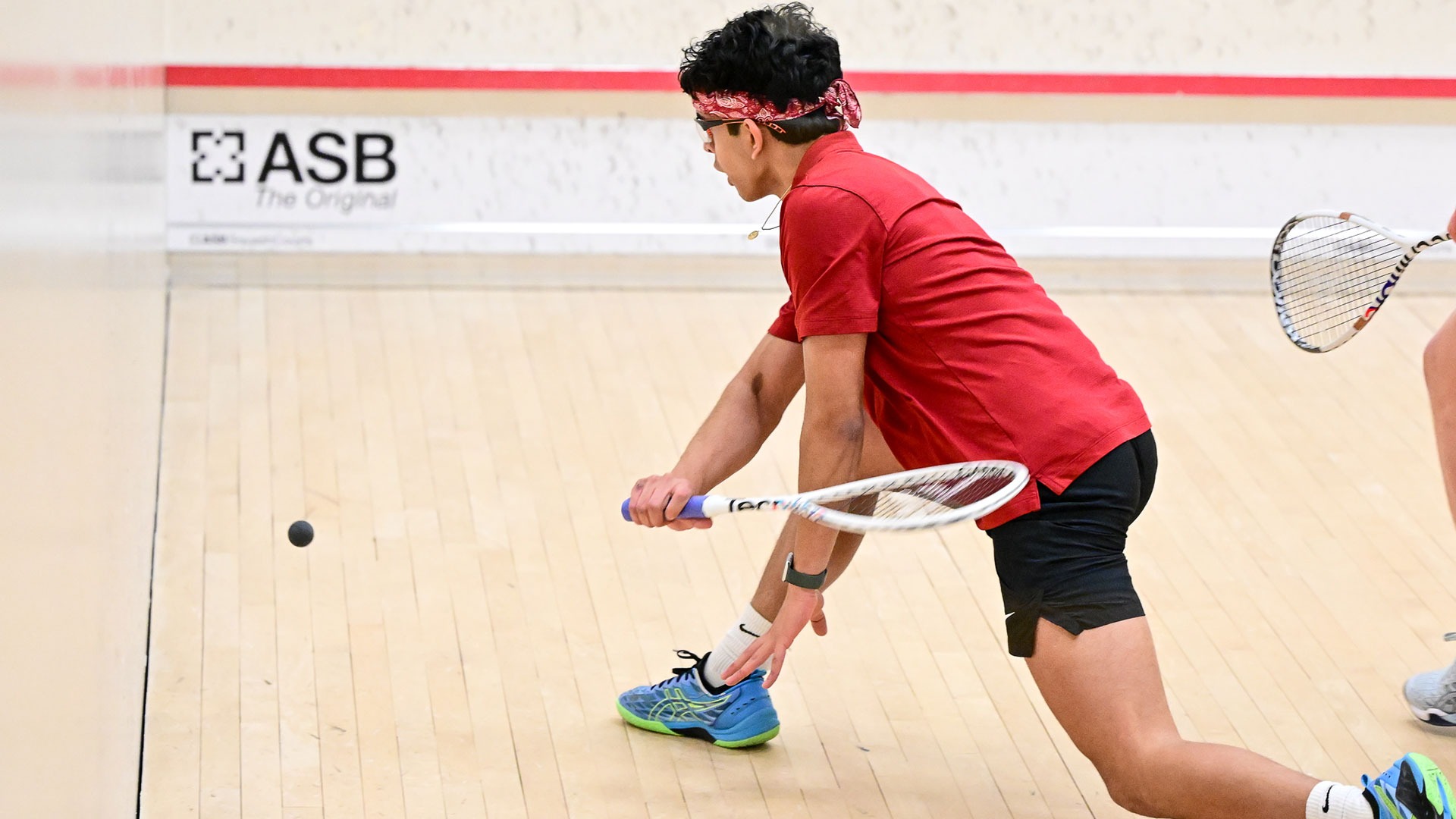 Rishabh Sharma hitting a squash ball