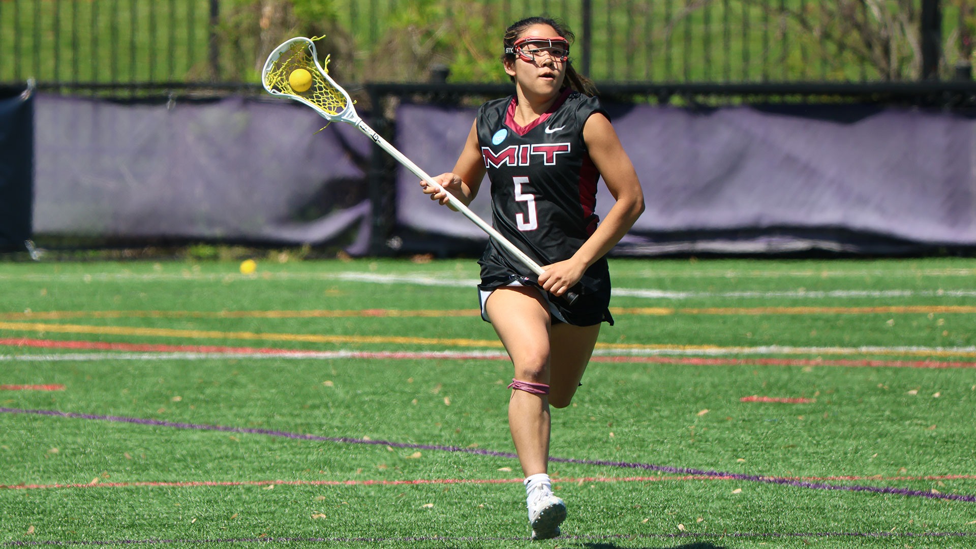 Annica Lam running down the field with the ball in her lacrosse stick