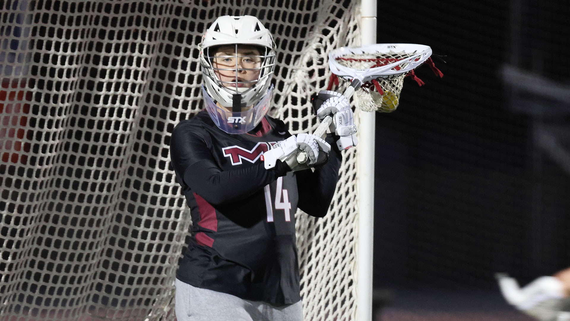 Pauline Vien standing in front of the goal with a ball in her lacrosse stick