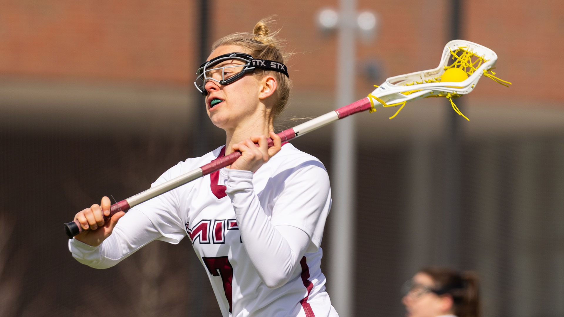 Lydia Birknes running down the field with the ball in her lacrosse stick