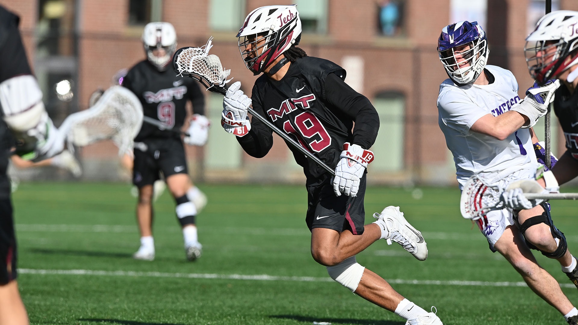 Riley Pierce running down the field with the ball in his lacrosse stick