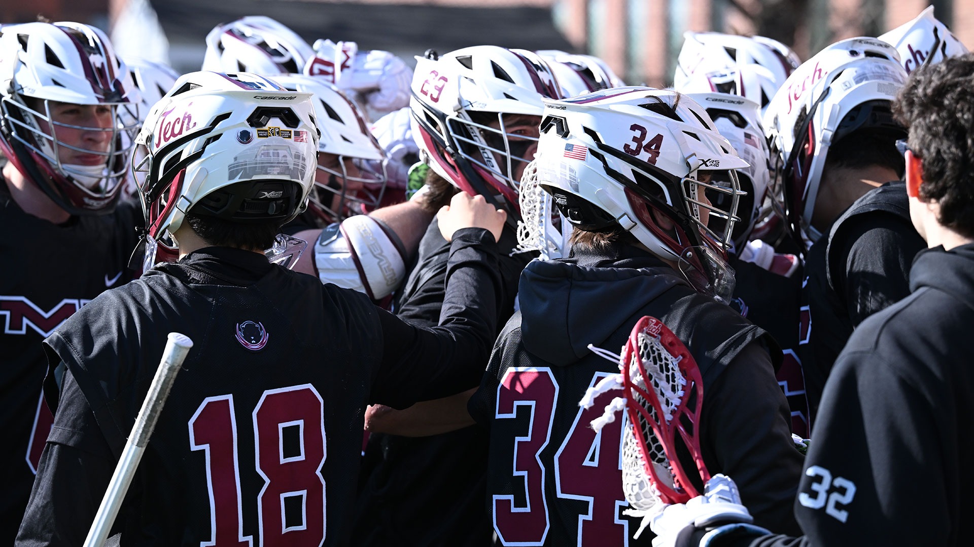 The men's lacrosse team standing in a huddle