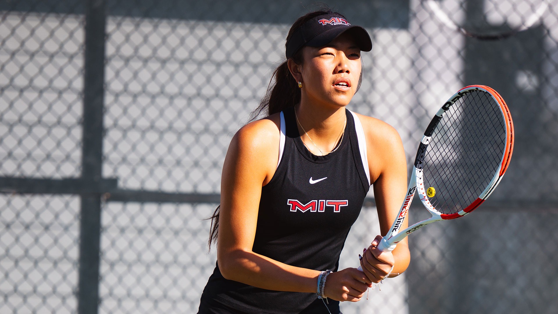 Carley Chen standing and holding her tennis racket