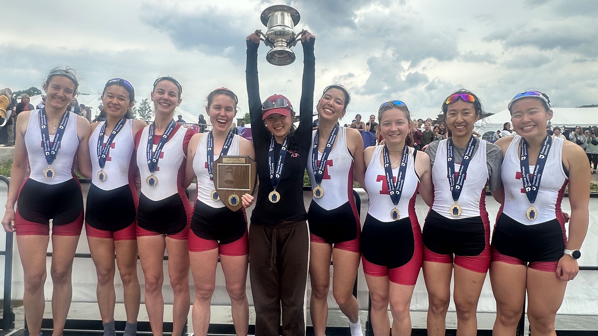 Women's lightweight crew varsity eight celebrates on the podium with a trophy and medals