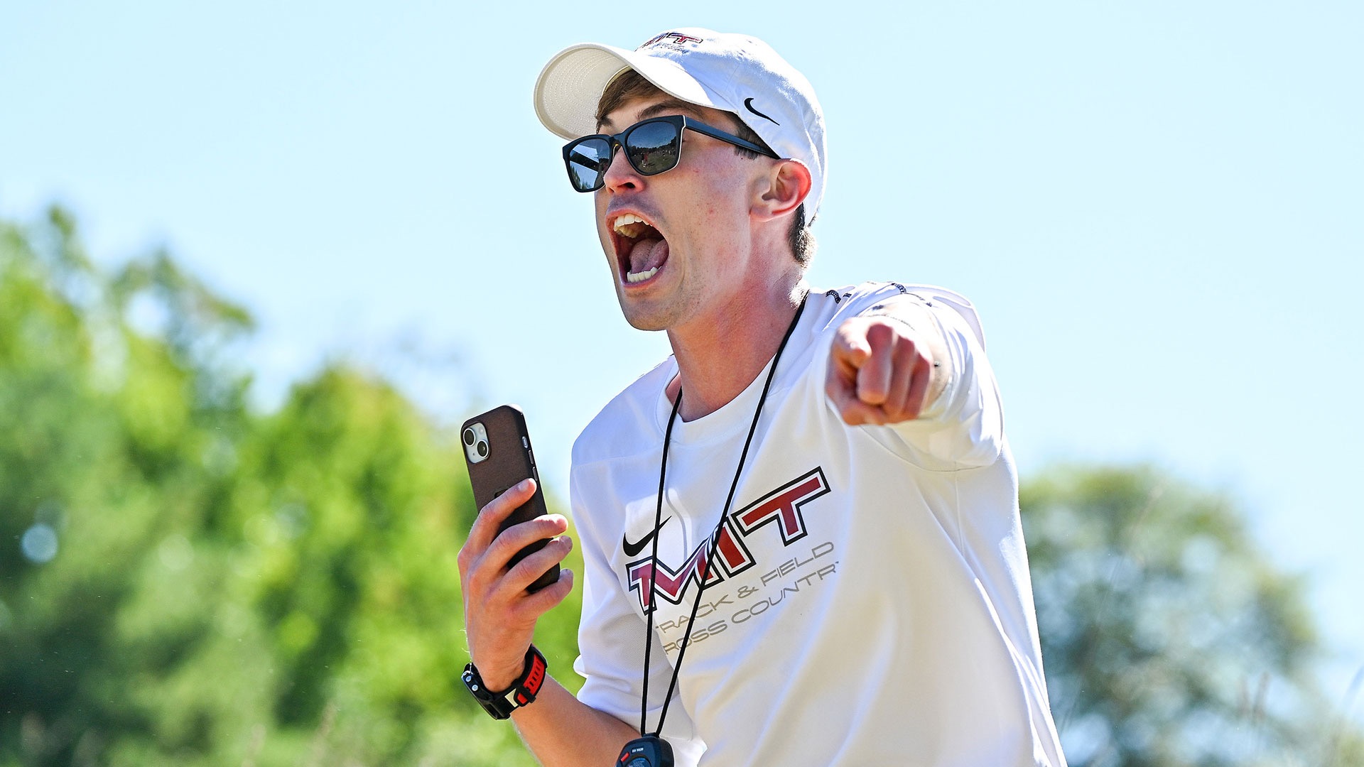 Riley Macon coaching holding a phone and stopwatch