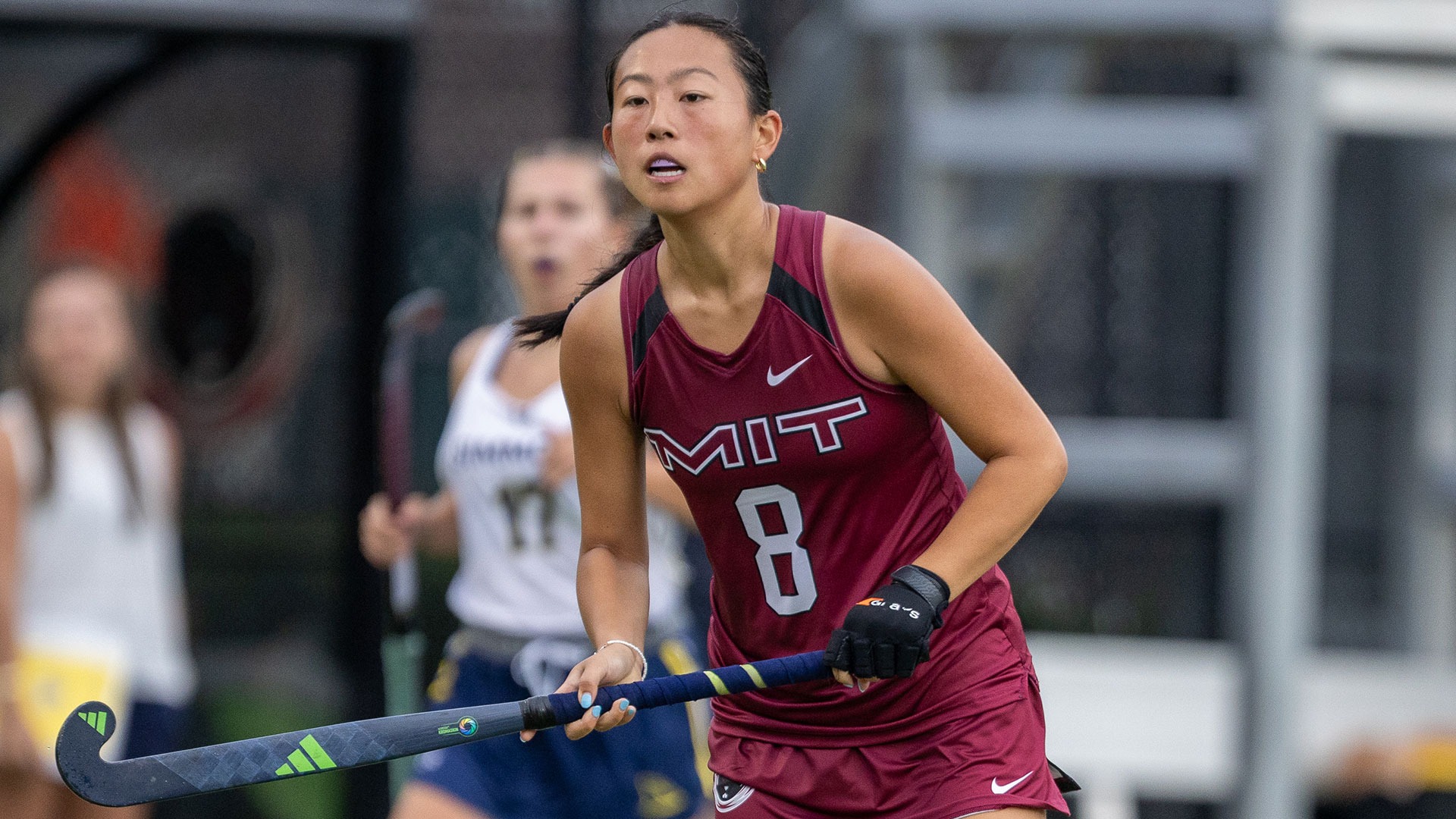 Meredith Wu running down the field while holding her field hockey stick