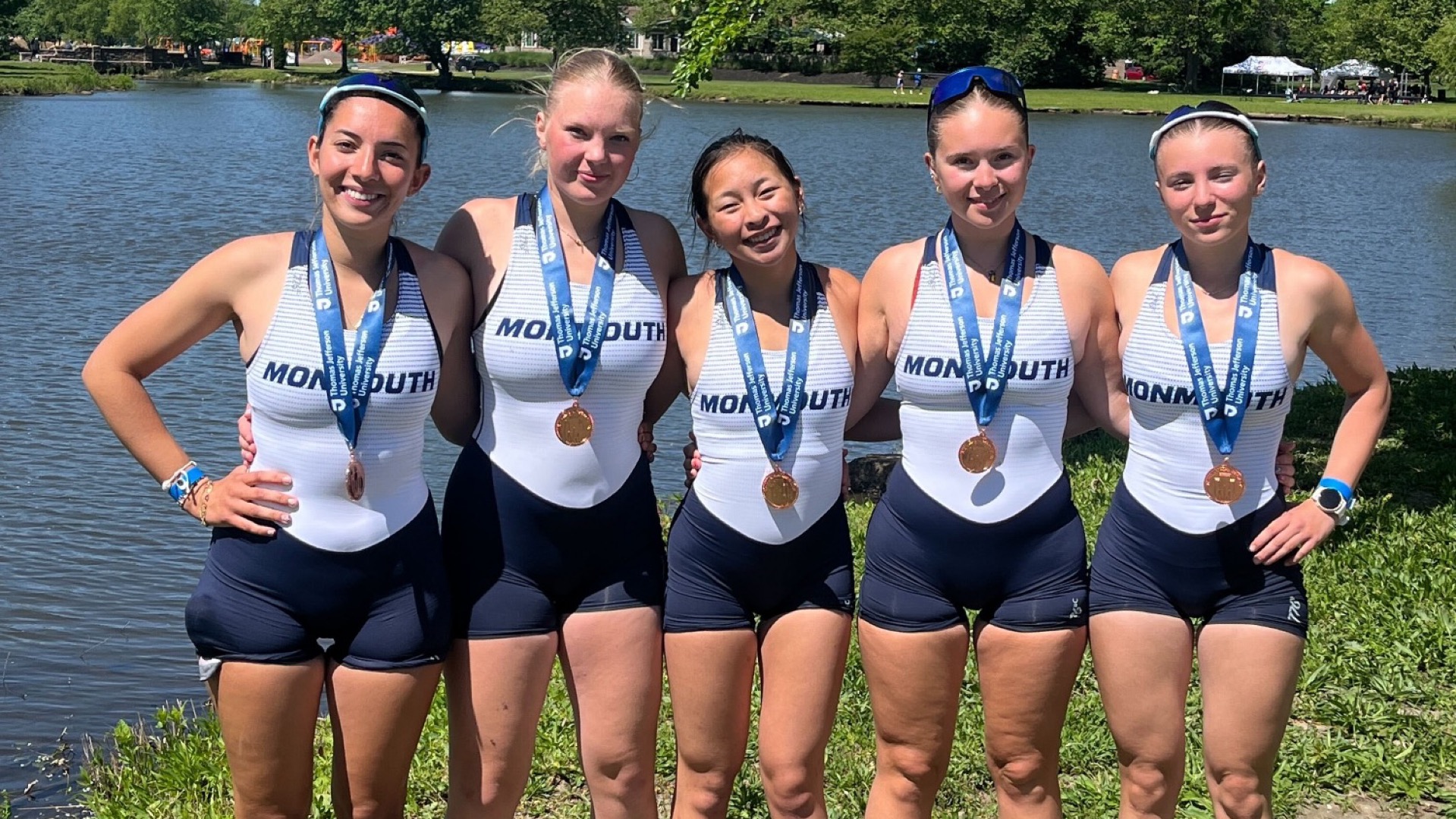 The Monmouth Freshman 4+ stand with their arms around each other and medals