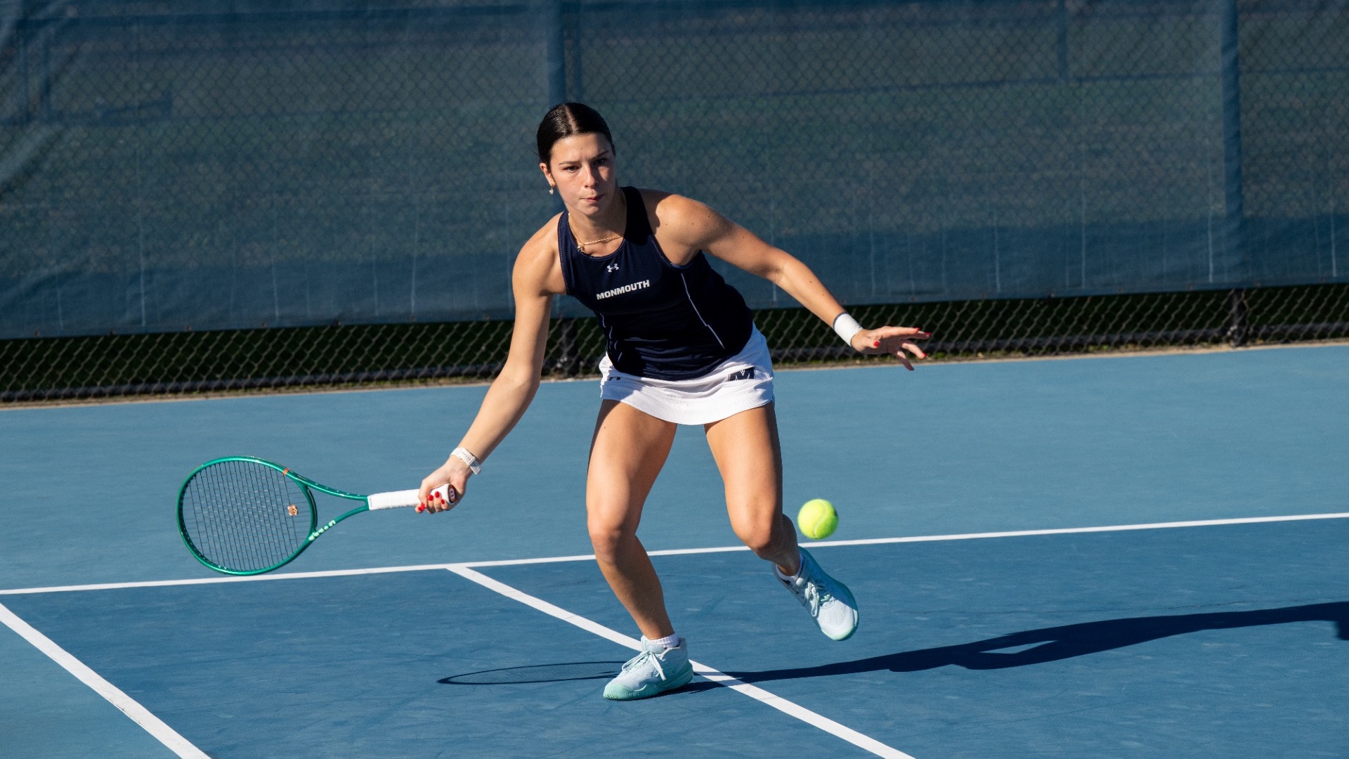 Emilia Julin moves forward with her racket extended to hit the ball