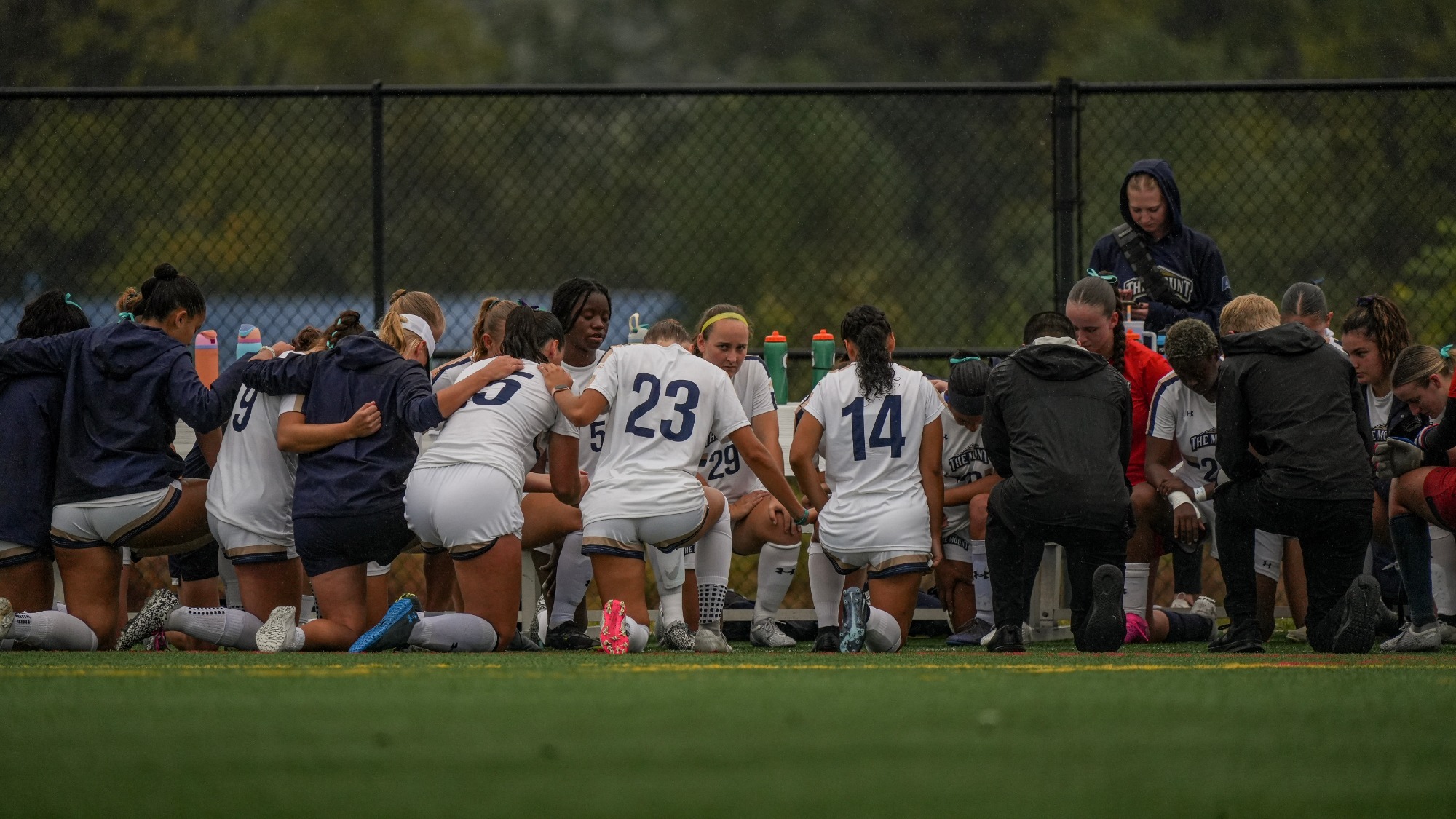 Women's Soccer Kneels as a Team for Reflection Before a Match