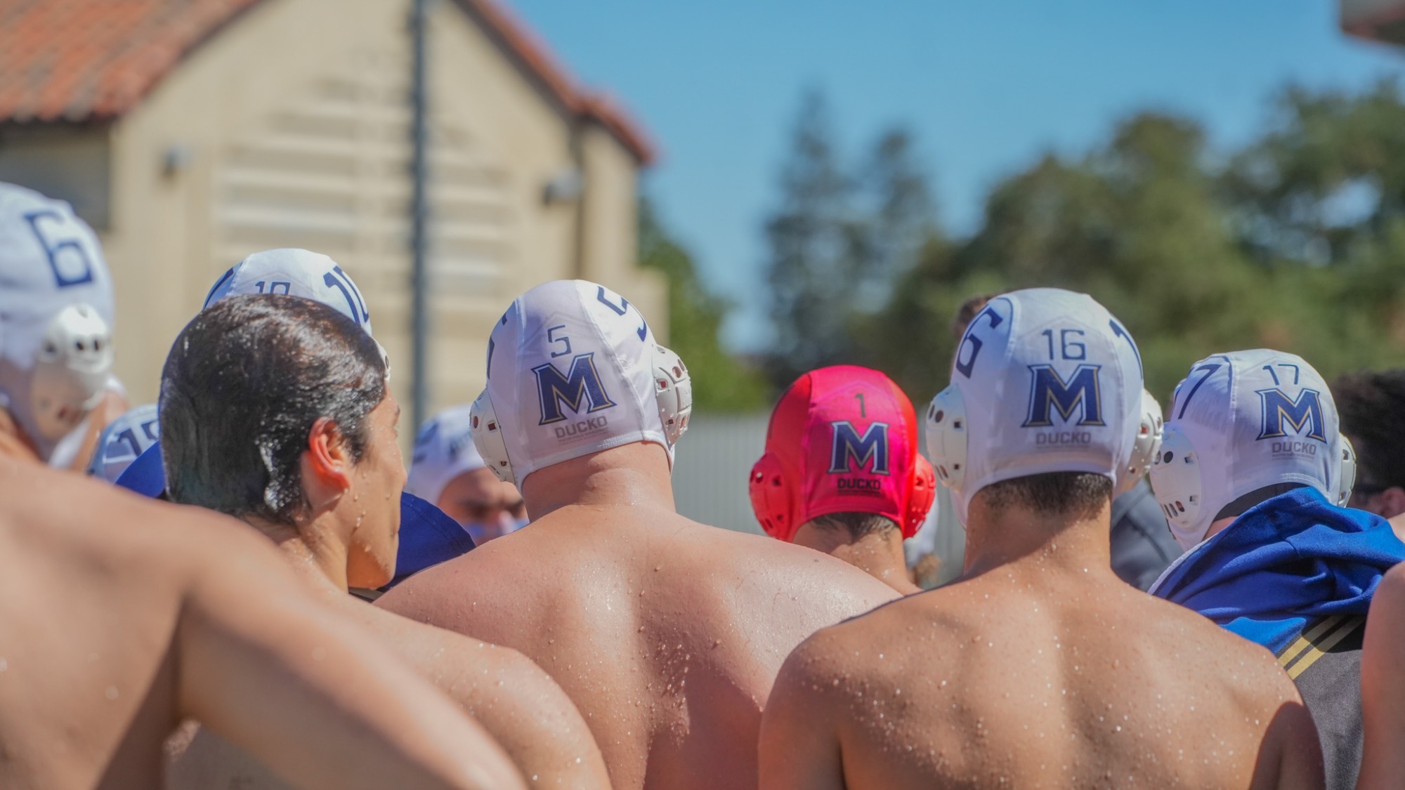 Mount St. Mary's men's water polo huddled with caps on