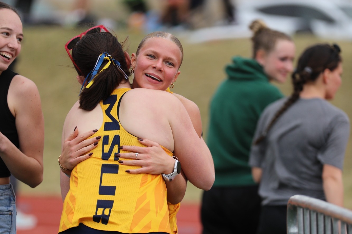 Micah Strong is hugged by her teammates after breaking the MSUB school record in the 800m at the Yellowjacket/Battlin' Bears Open