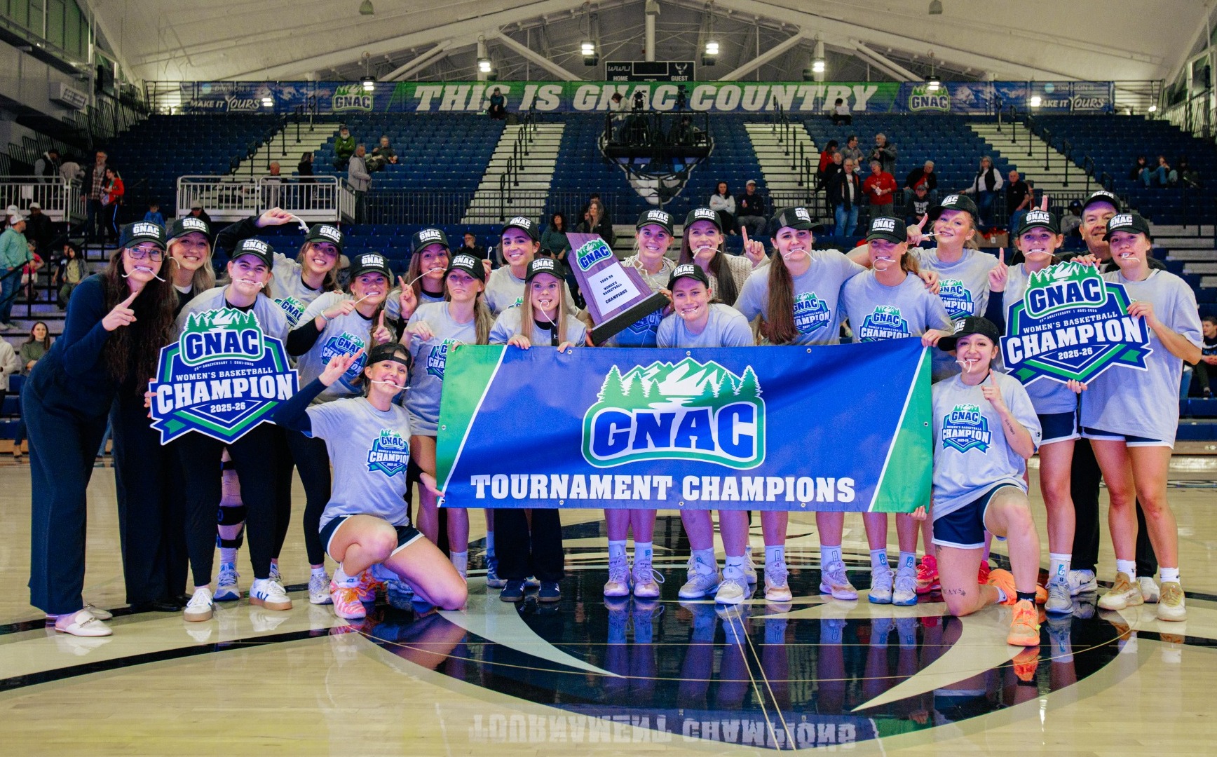 The MSUB women's basketball team poses at midcourt to celebrate it's GNAC Championship title