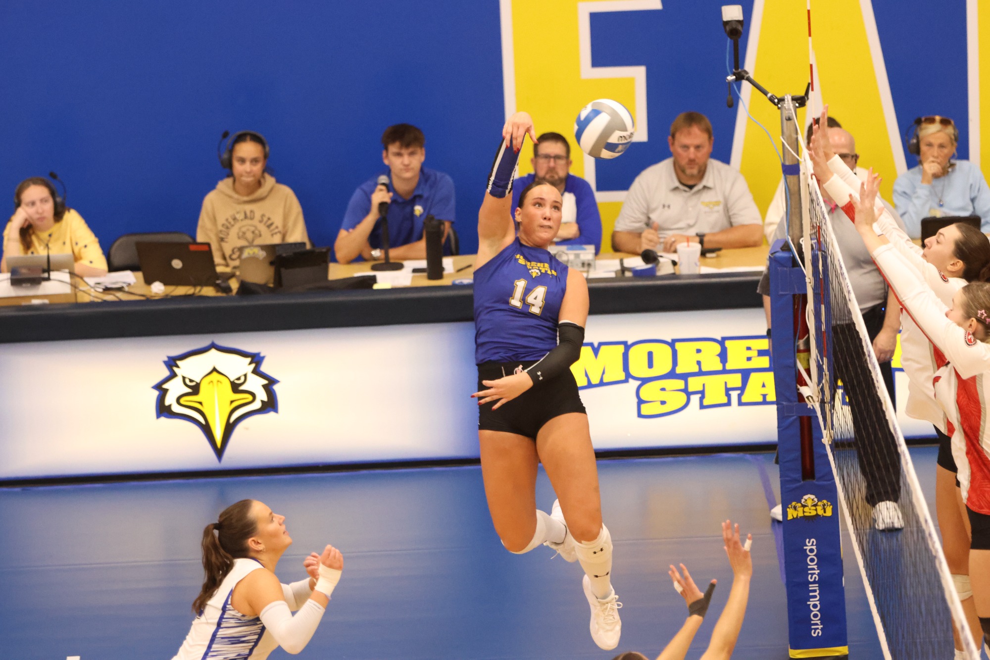 Blonde girl in blue volleyball jersey hit a volleyball 