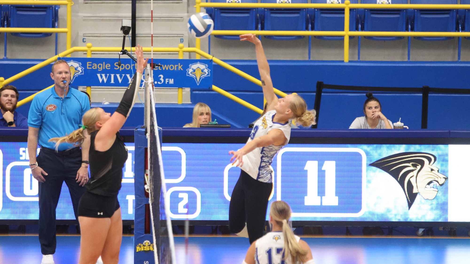 Blonde woman in white jersey hits a volleyball