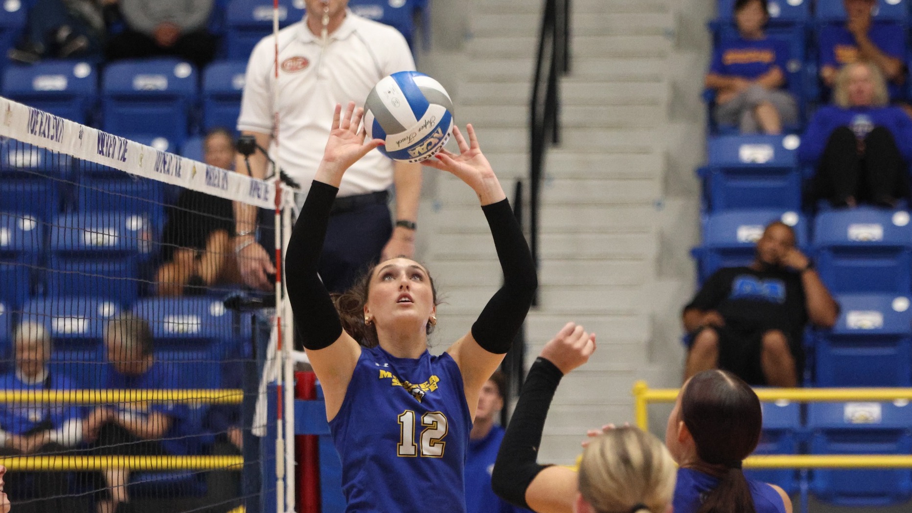 Dark-haired girl in blue jersey with two hands touching ball
