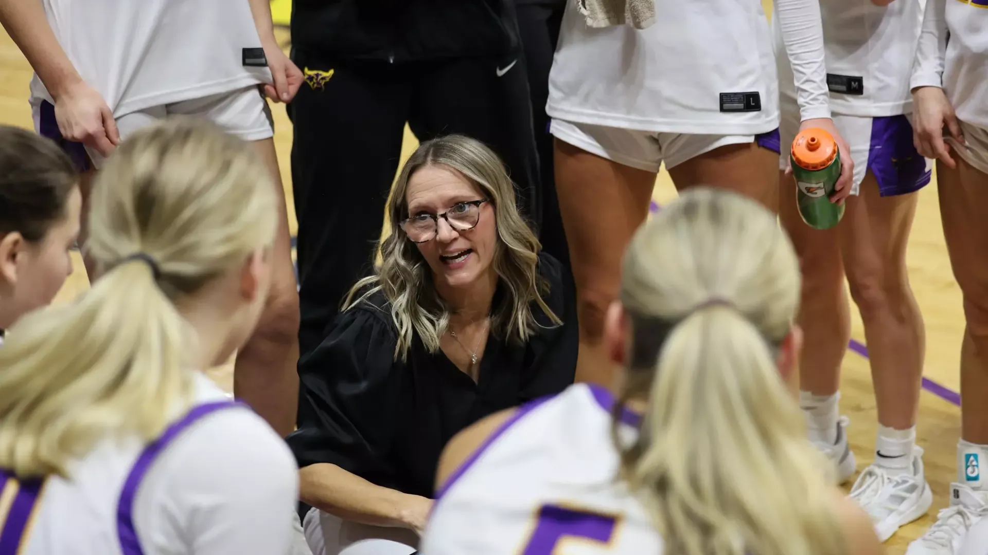 Head Coach Emilee Thiesse addresses her women's basketball team in a huddle
