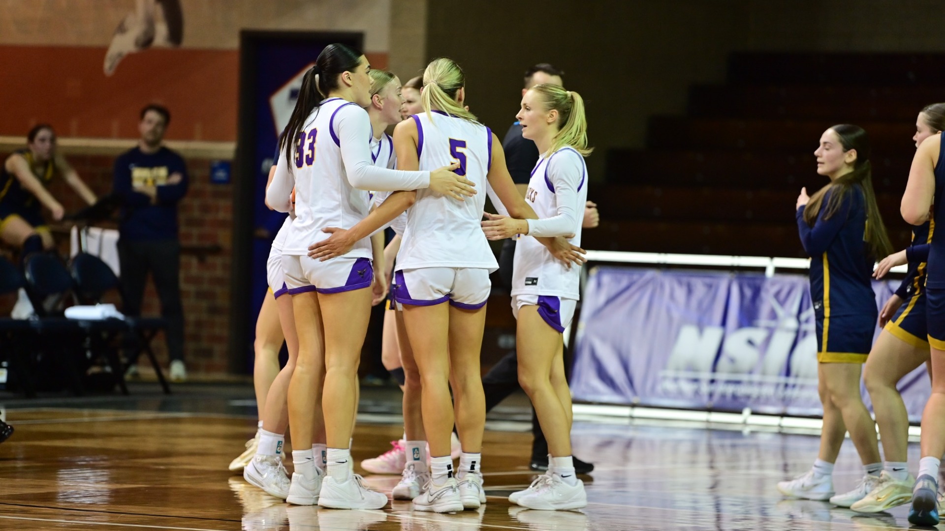 Women's Basketball team huddle on the court at the NSIC Championship Game