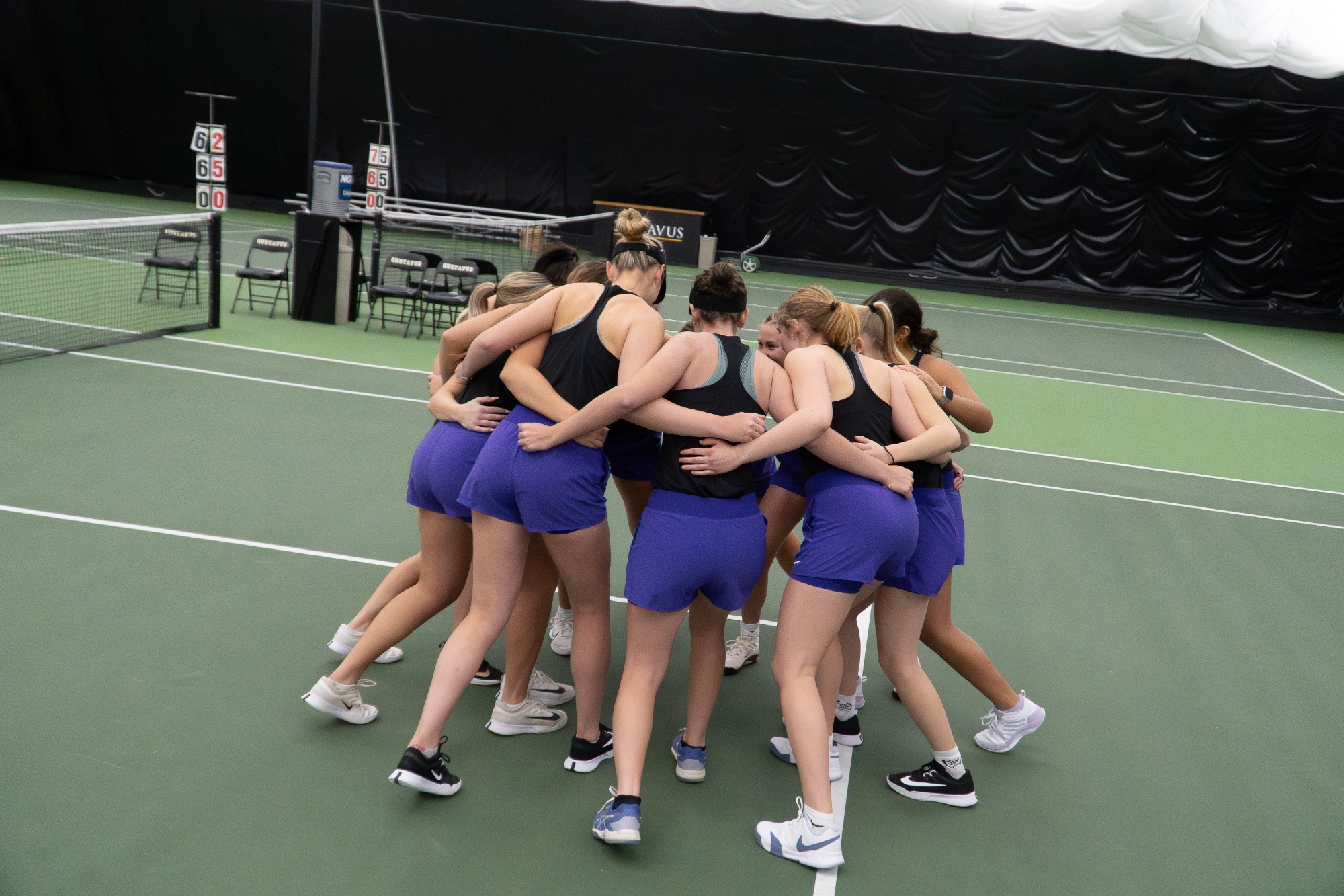 The tennis team in a huddle before the start of the dual